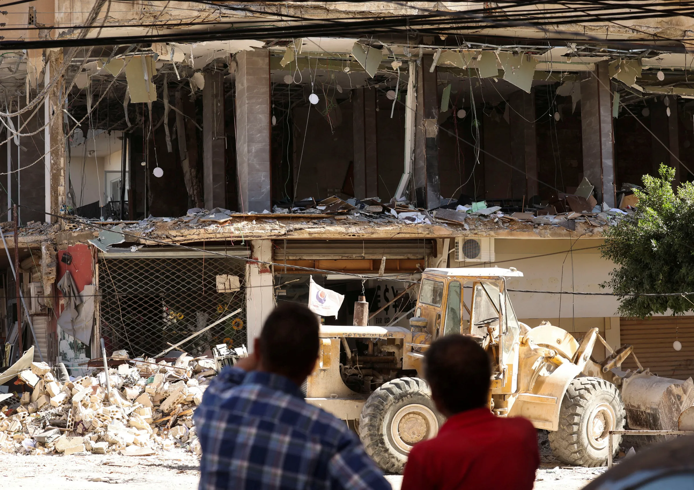 People stand near a damaged branch of ‘Al-Qard al-Hassan', in the aftermath of Israeli airstrikes on Sunday that hit several branches of the financial institution linked to Lebanon's Hezbollah, in Tyre, Lebanon, October 21, 2024. REUTERS/Aziz Taher