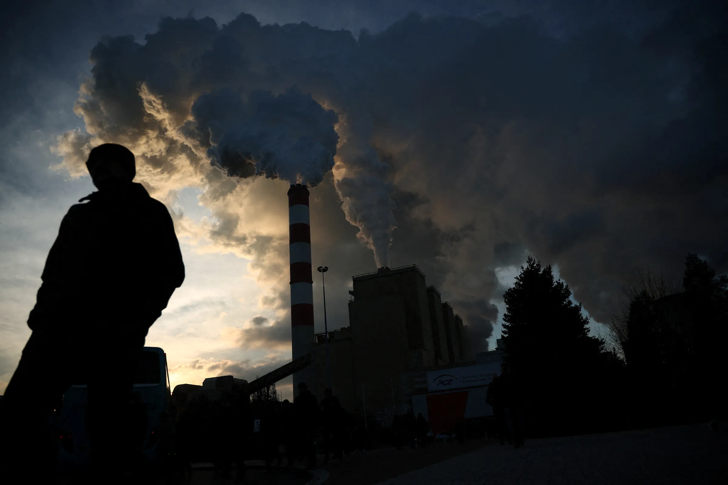 A man walks as smoke and steam billow from Belchatow Power Station, Europe's largest coal-fired power plant, in Rogowiec, Poland, November 22, 2023. REUTERS/Kacper Pempel