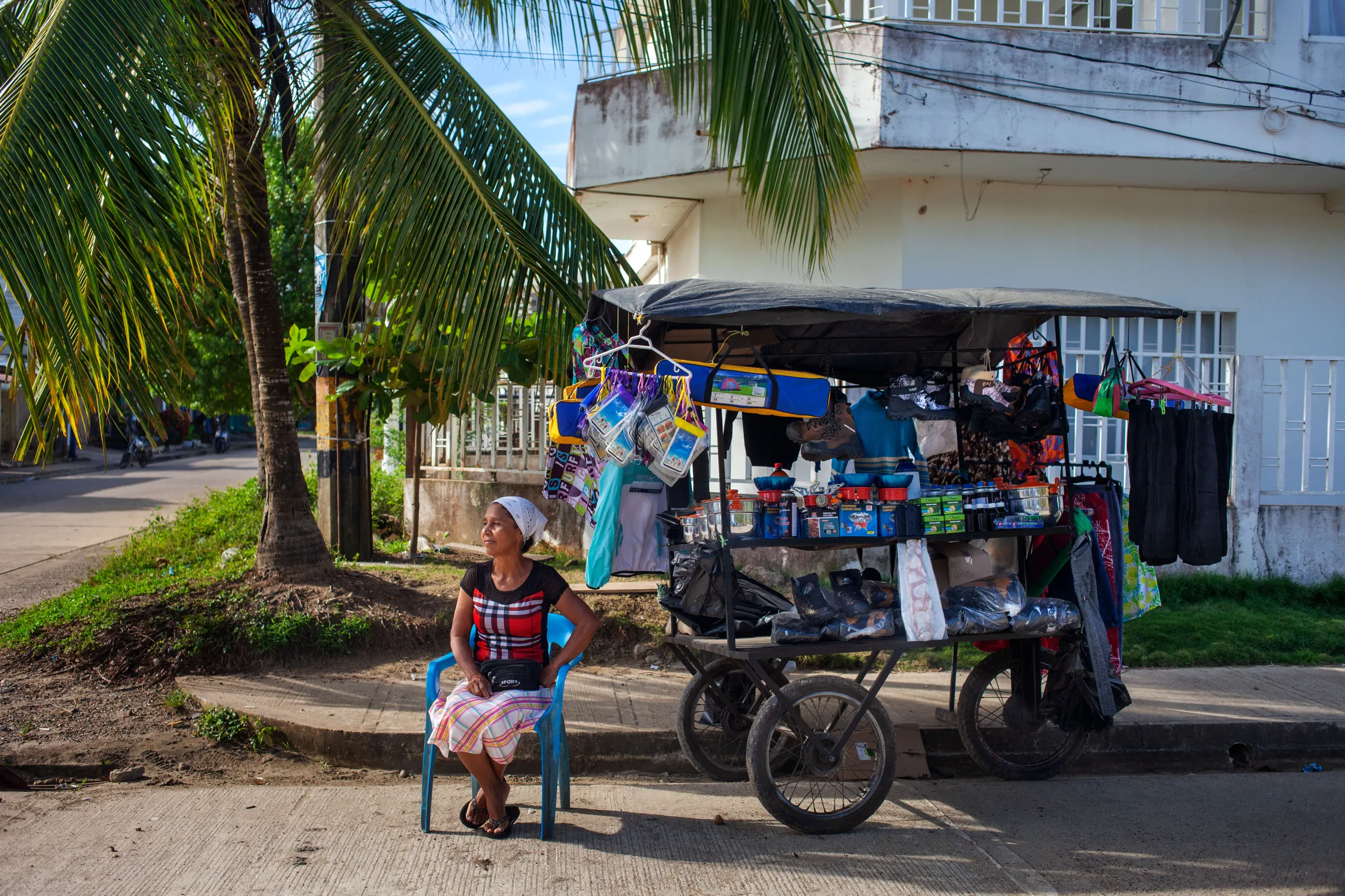 Street seller Graciela Leon sits next to her stall selling jungle kit to migrants in the Colombian beach town of Necoclí along the main beachfront promenade. About 750 migrants on average a day passed through Necoclí this year. Necoclí, Colombia, July 29, 2022. Thomson Reuters Foundation/Fabio Cuttica