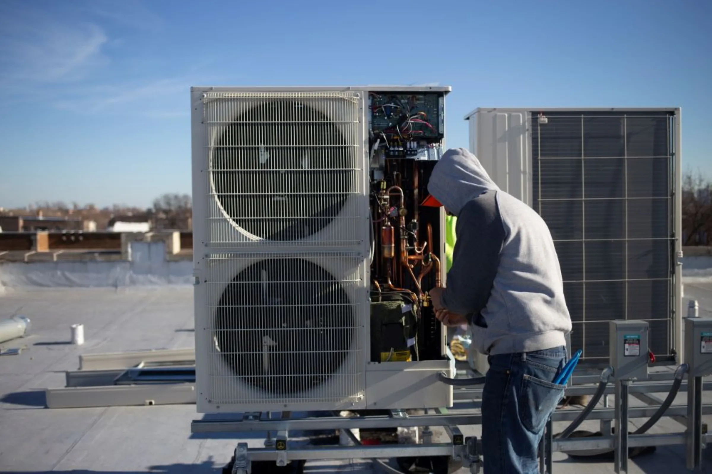 A worker installs a heat pump unit as part of a building electrification project in Chicago in spring 2022. Elevate/Handout via Thomson Reuters Foundation