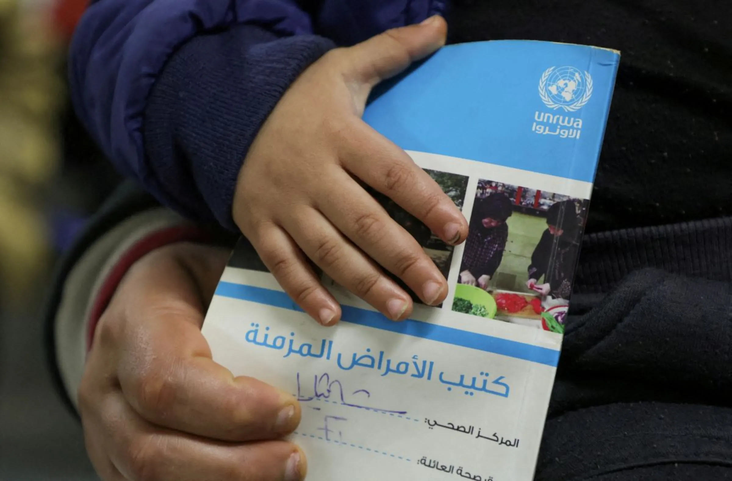A child holds a booklet as he waits inside a United Nations Relief and Works Agency (UNRWA) health center at Shatila Palestinian refugee camp, in Beirut suburbs, Lebanon January 30, 2024. REUTERS/Mohamed Azakir