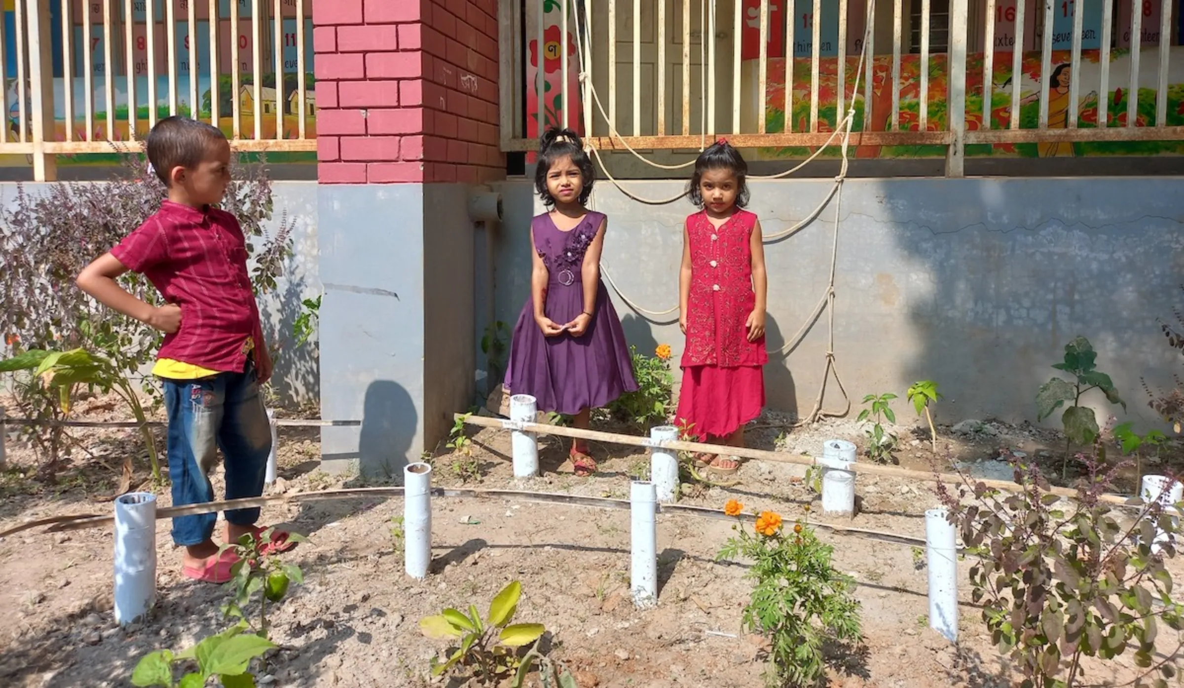 Children pose for a picture in front of plants they have been growing in the small garden next to their school building, Gazipur, Bangladesh, November 11, 2023