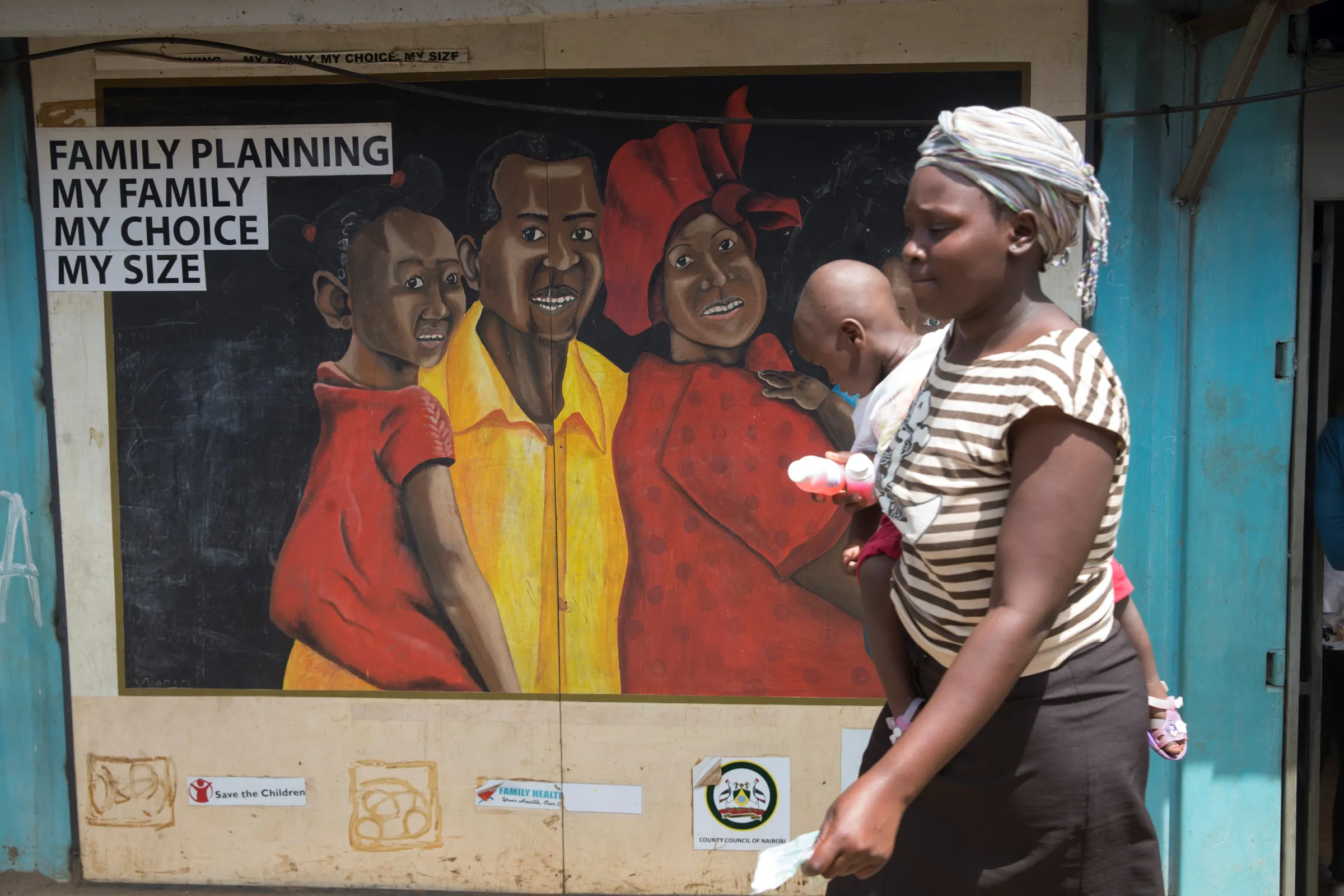 A woman walks past a murel during a visit by The Netherlands Minister for Trade and Development Cooperation Lilianne Ploumen at a Family Health Options clinic in the Kibera slums in Nairobi, Kenya, May 16, 2017. picture taken May 16, 2017.REUTERS/Baz Ratner