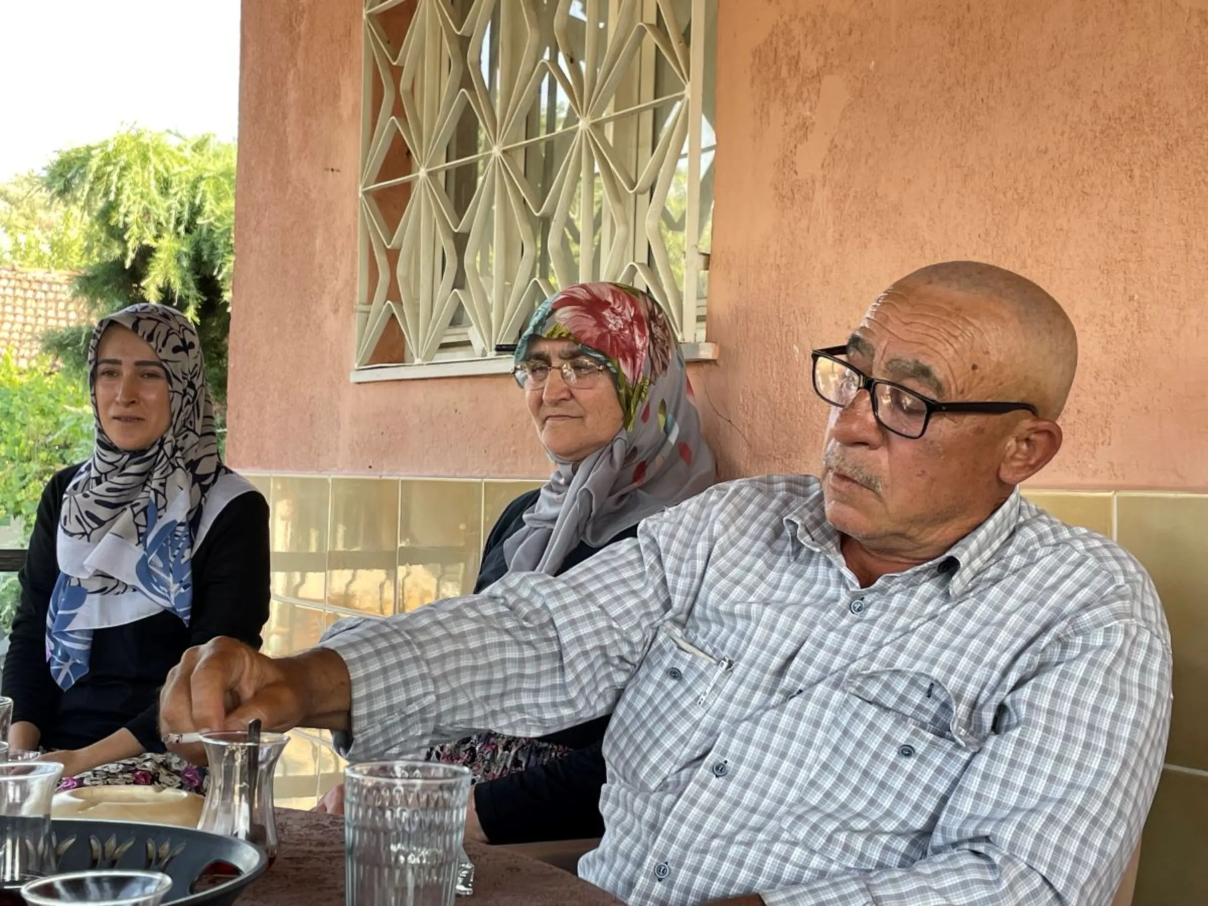 Retired fisherman Suleyman Pekkara, 62, sits on the veranda of his home with his family, in Tekelioglu, Manisa, Turkey. July 13, 2023. Thomson Reuters Foundation/Beatrice Tridimas