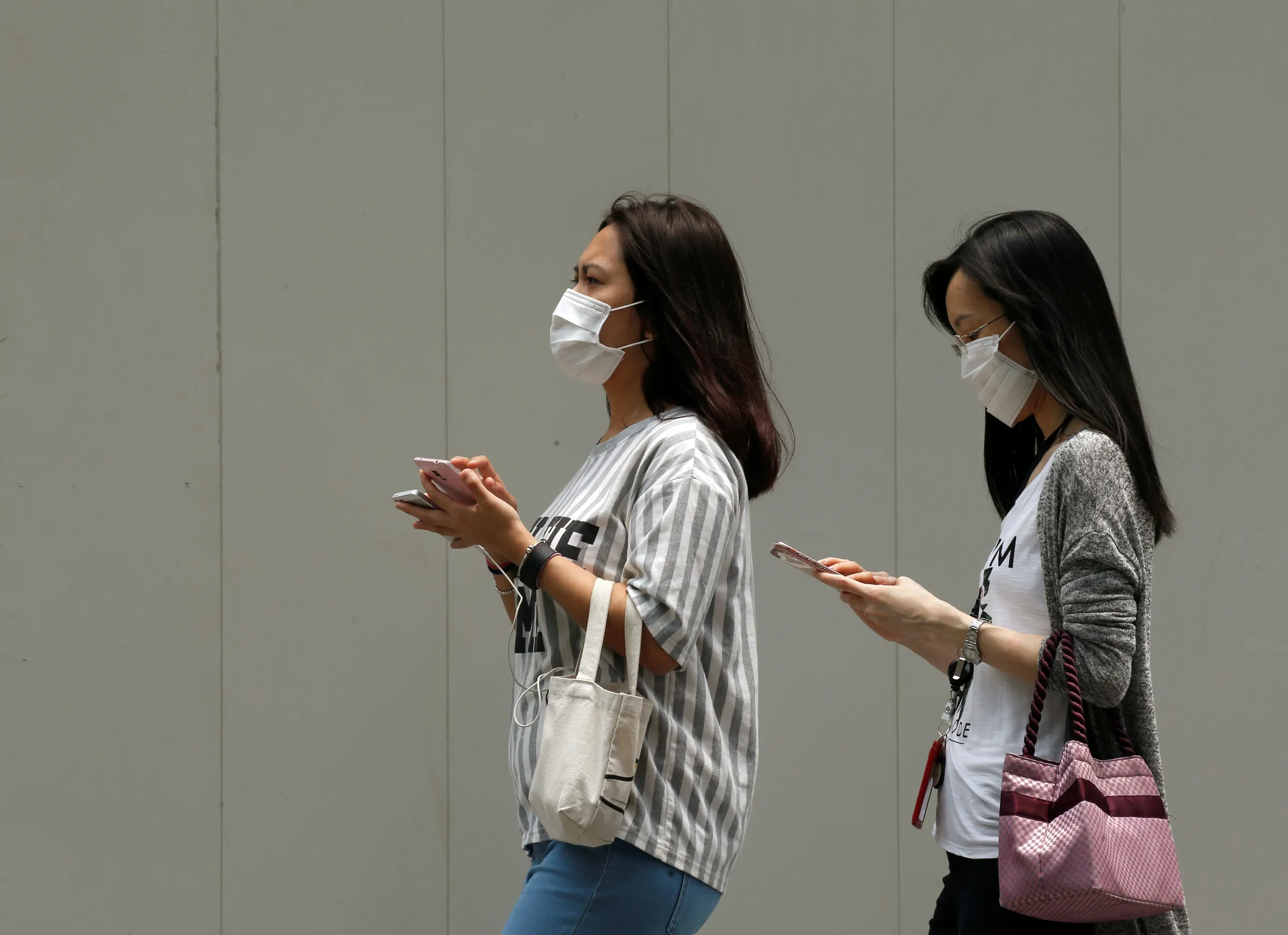 Women wearing face masks use their mobile phones as haze shrouds Singapore's central business district August 26, 2016. REUTERS/Edgar Su