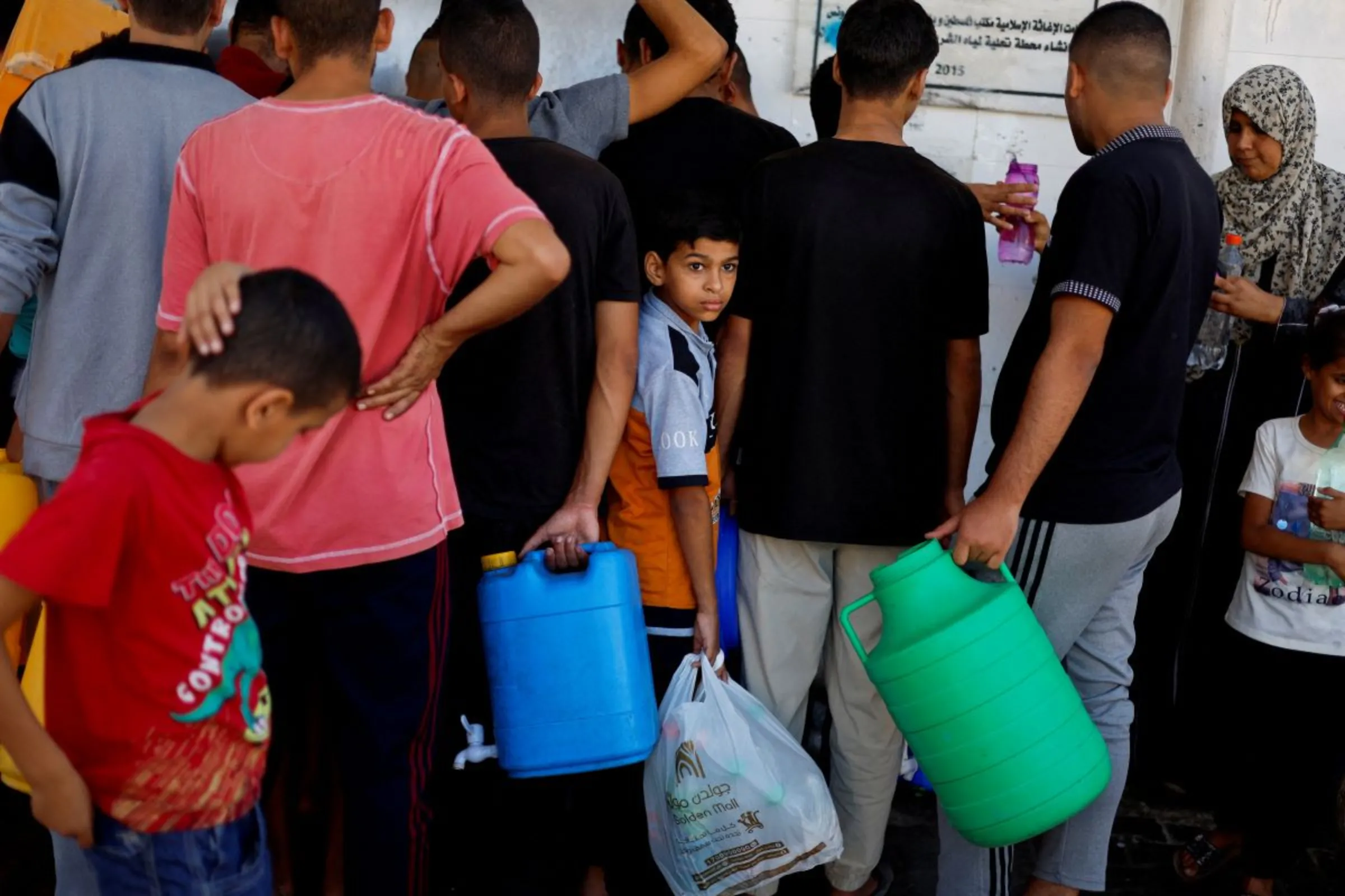 Palestinians gather to collect water, amid shortages of drinking water, as the Israeli-Palestinian conflict continues, in Khan Younis in the southern Gaza Strip October 15, 2023. REUTERS/Mohammed Salem