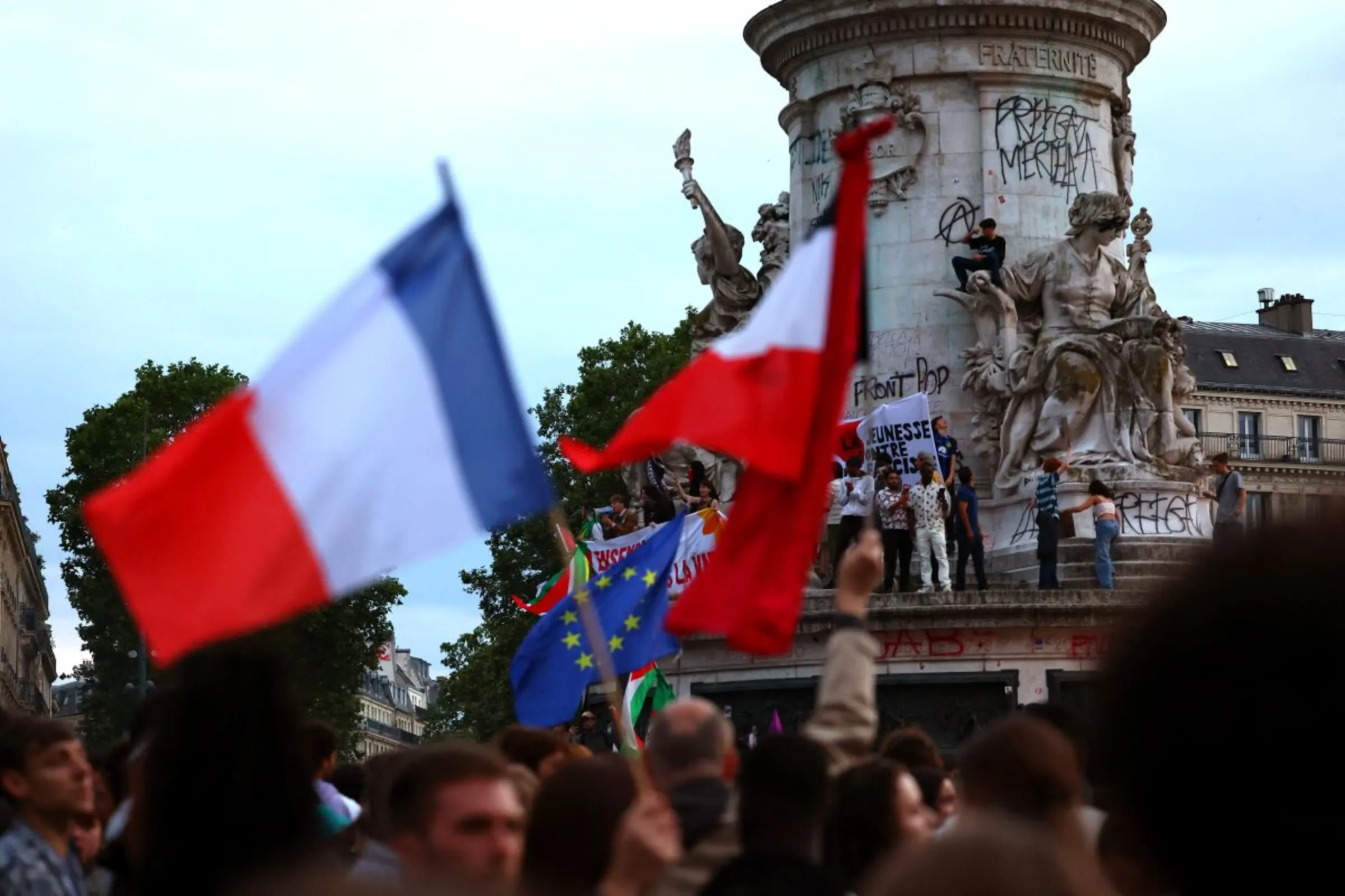 People hold French national flags as they gather to protest against the French far-right Rassemblement National (National Rally - RN) party, in Paris, France, June 30, 2024. REUTERS/Fabrizio Bensch