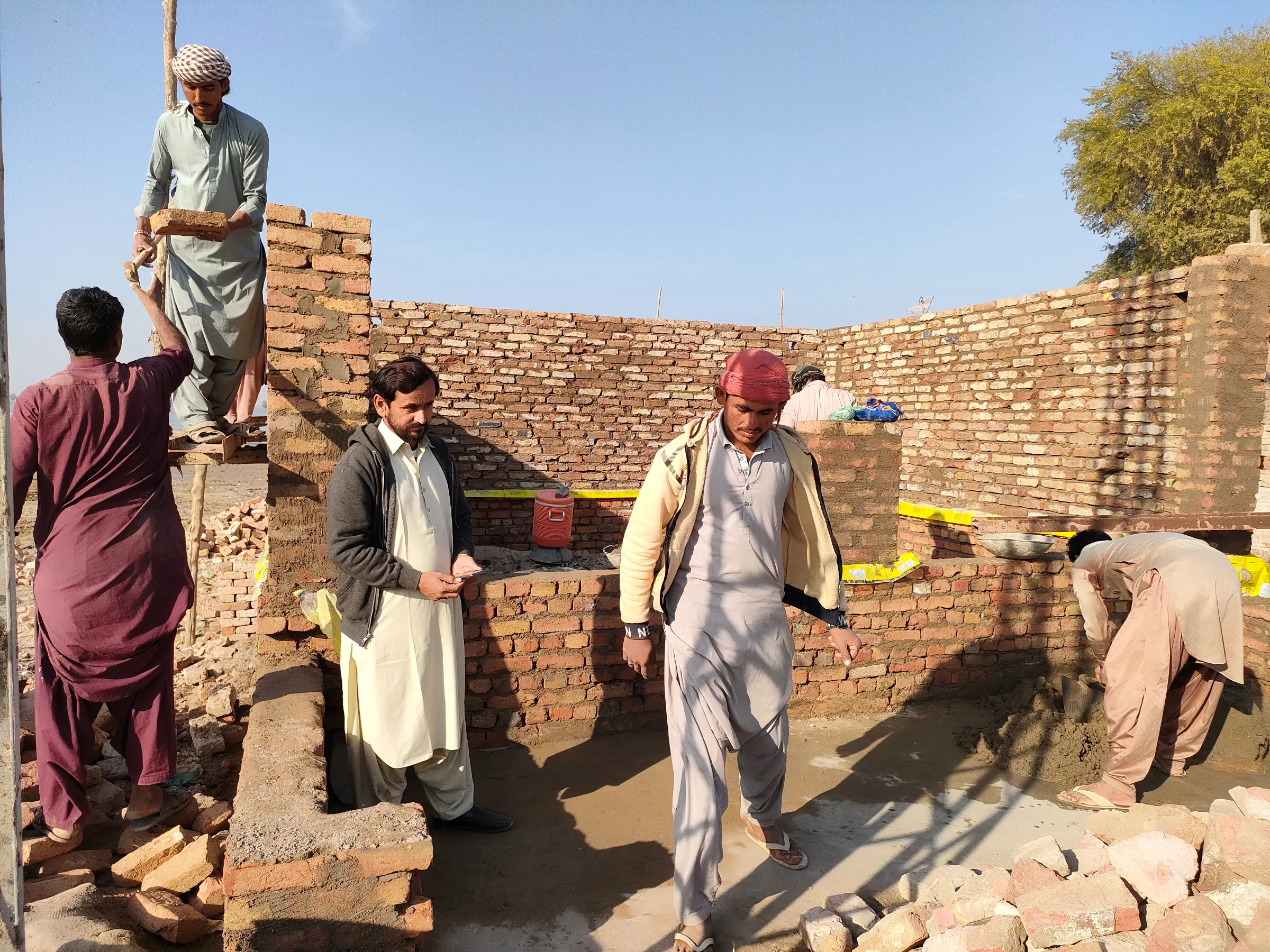 Shop owner Muhammad Fazal oversees the rebuilding of his general store in a market in village Gozo, Pakistan. January 17, 2023. Thomson Reuters Foundation/Waqar Mustafa