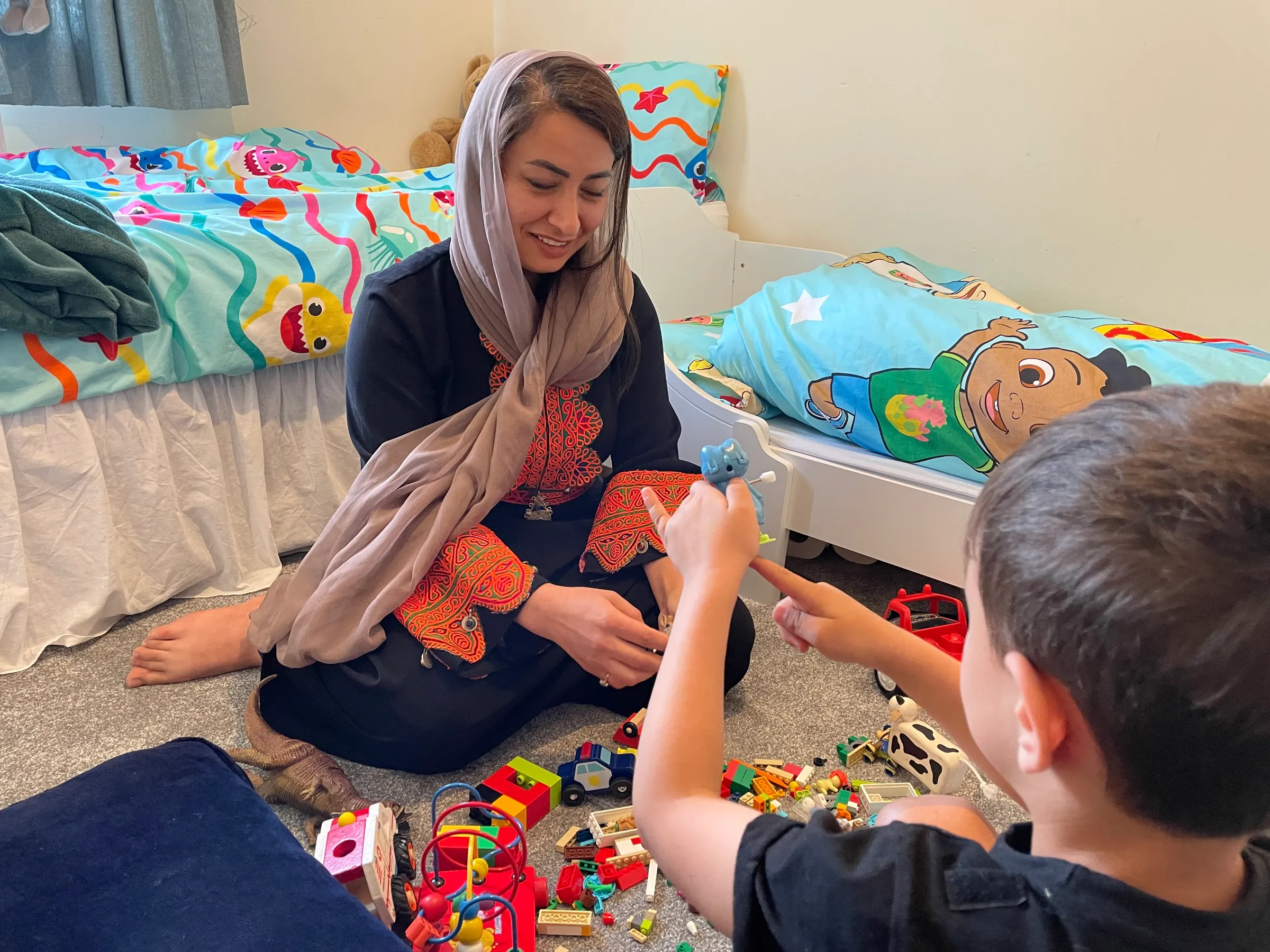 A woman plays with her son in a child's bedroom