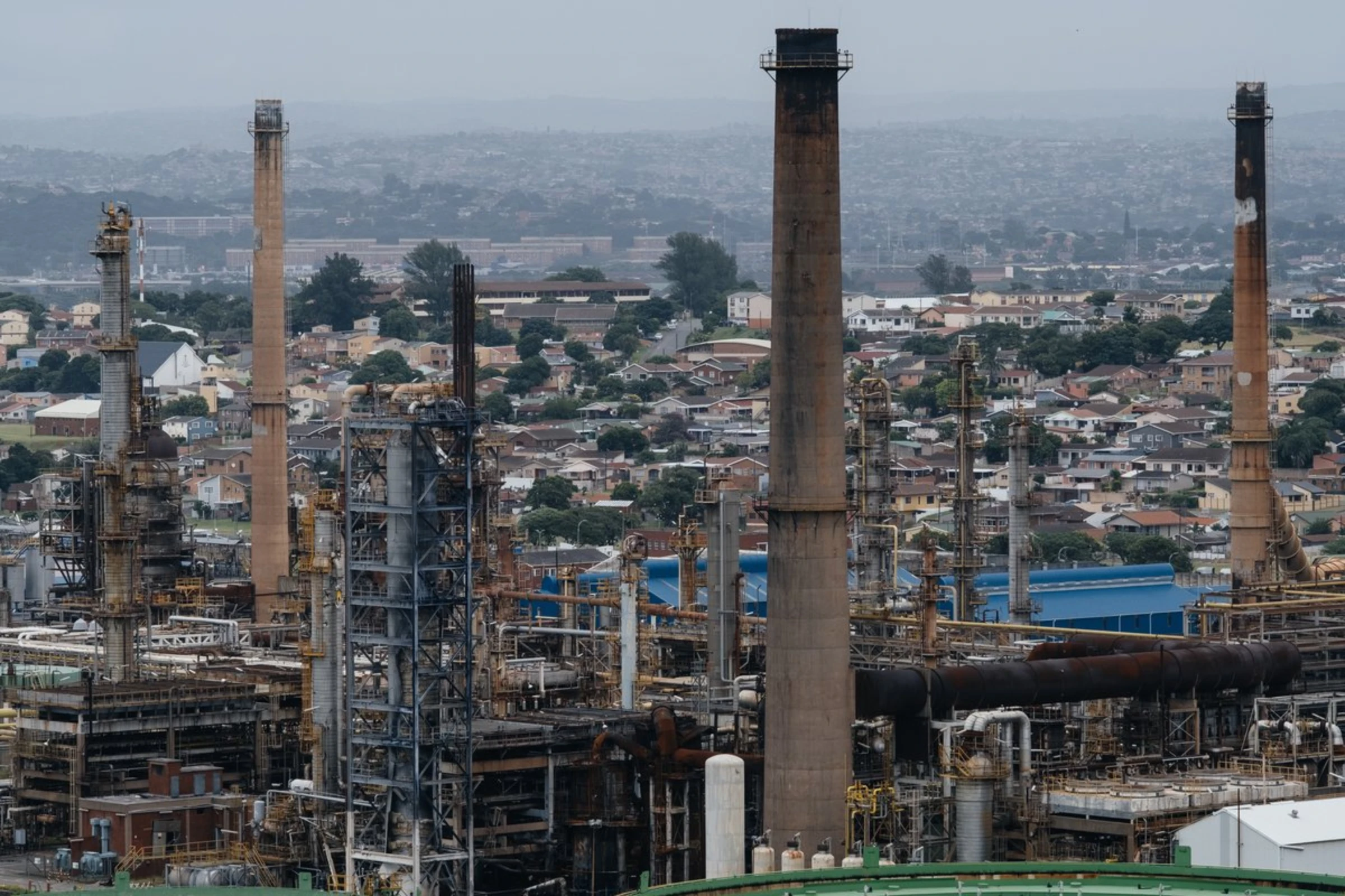 Smoke stacks at the Engen oil refinery tower over residential areas in the south of Durban, South Africa, April 1, 2021