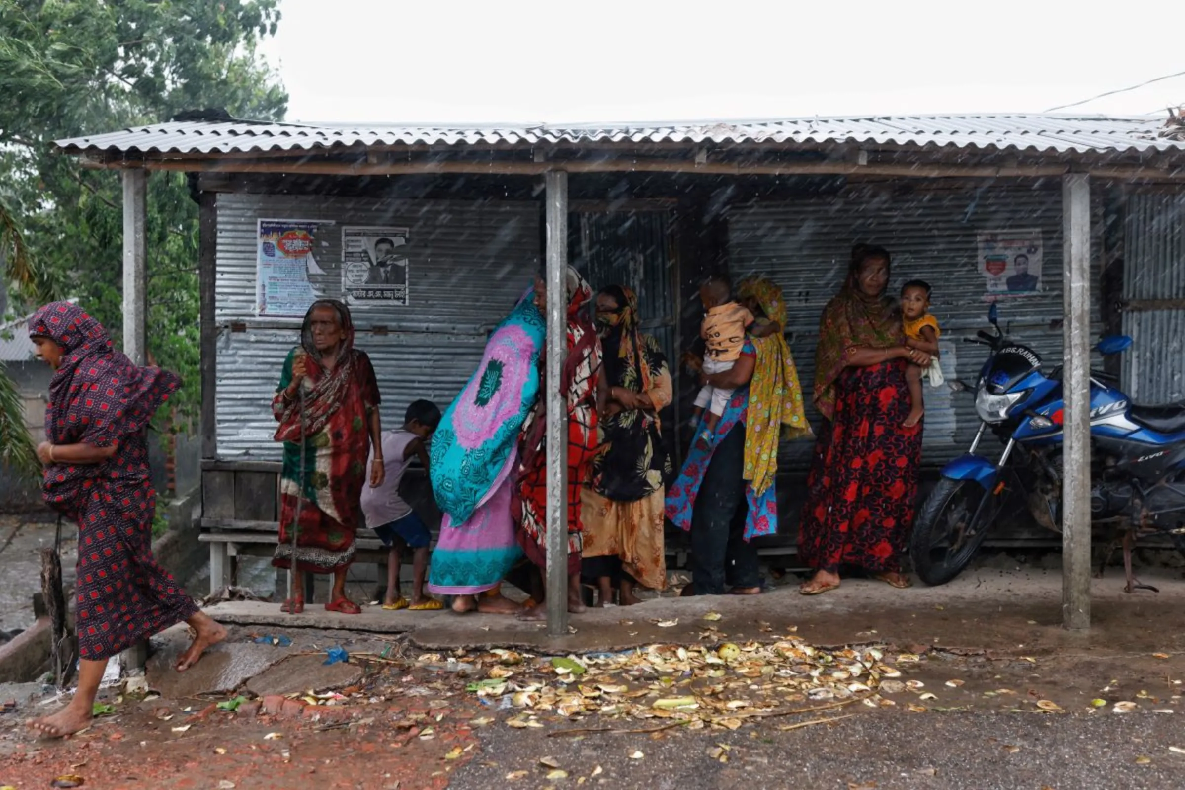 Women and children take shelter under a tin shed roof during rain ahead of Cyclone Remal, in Satkhira, Bangladesh, May 26, 2024. REUTERS/Mohammad Ponir Hossain