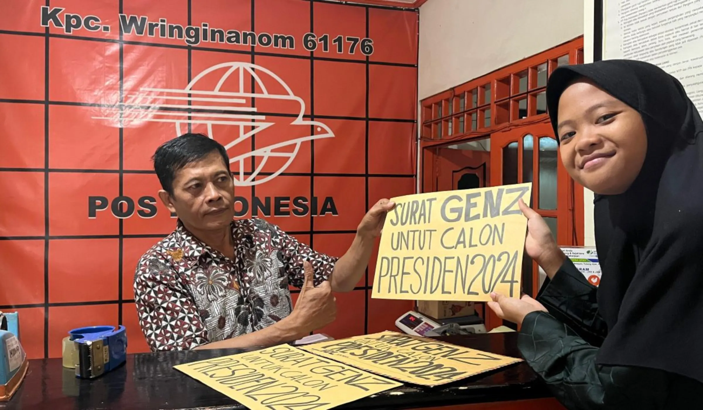 Aeshnina Azzahra Aqilani hands over the climate demand letters for the Indonesian presidential candidates to a postal worker, January 19, 2024.  Thomson Reuters Foundation/Asad Asnawi