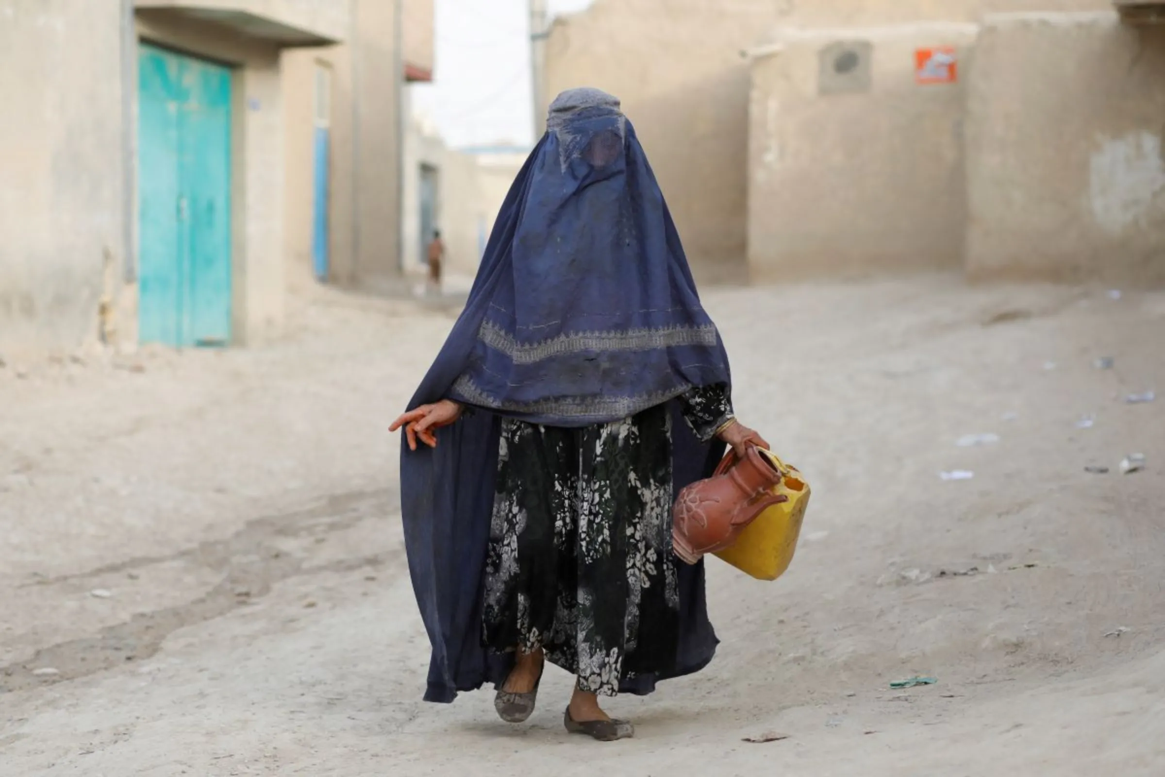 An Afghan woman carries empty containers to fetch water in Nahr-e-Shahi district in Balkh province, Afghanistan, August 6, 2023. REUTERS/Ali Khara