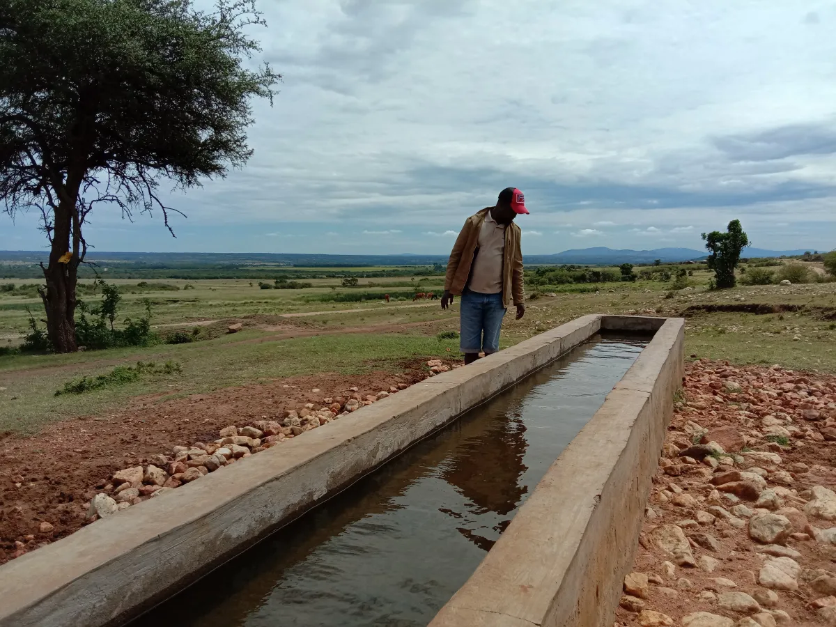 A man inspects a water trough that serves both livestock and wildlife