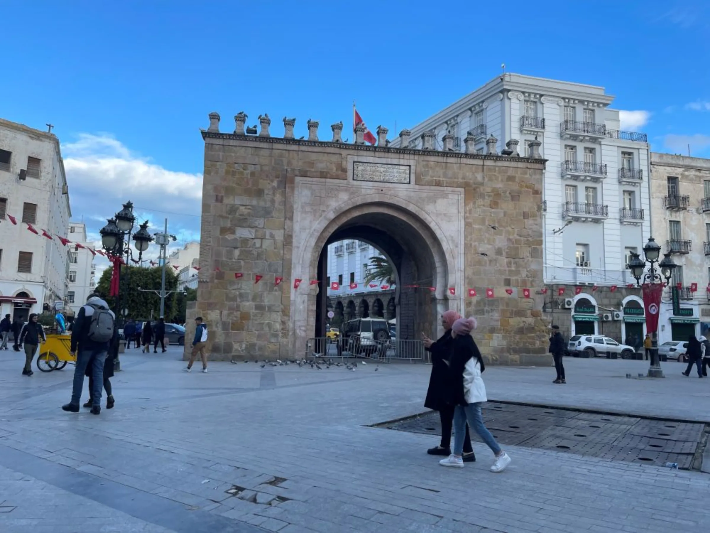 Two women walk past Bab El Bahr in central Tunis on January 29, 2023
