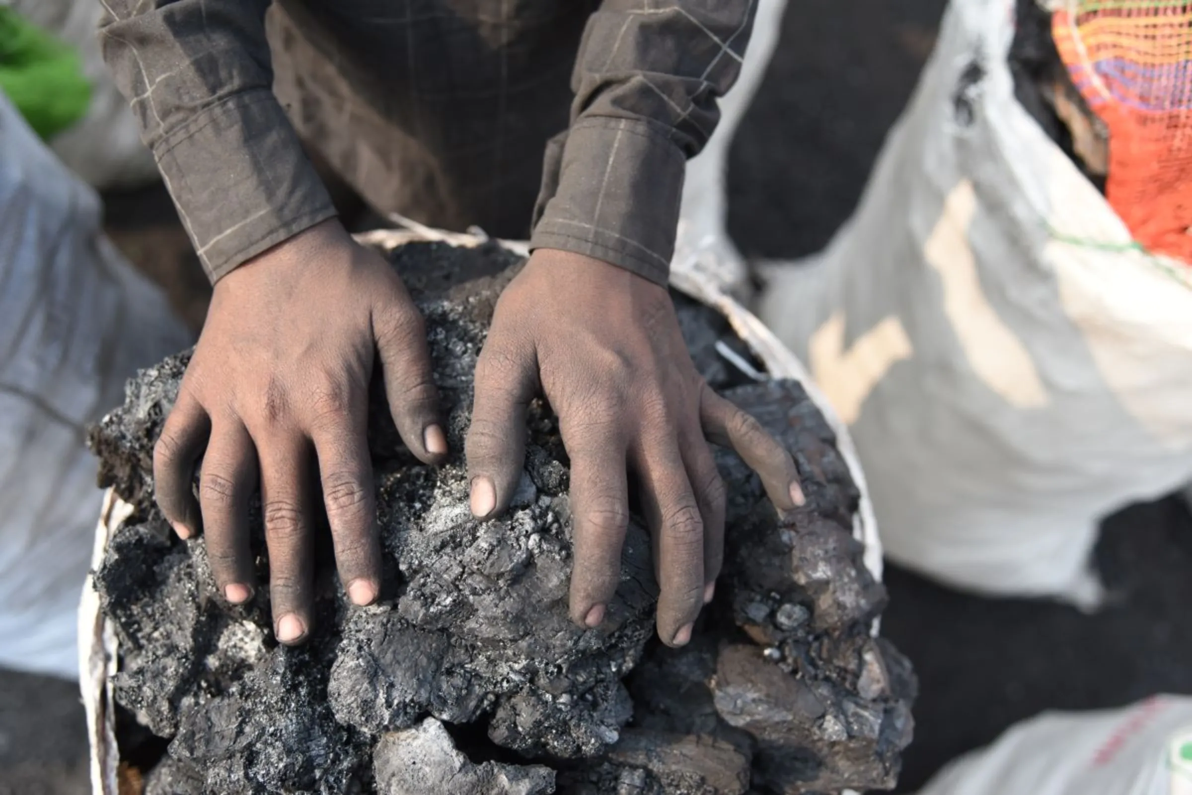 A child puts his hand on a basket of coal he has scavenged in a mining area of Jharia coalfield, India, November 11, 2022. Thomson Reuters Foundation/Tanmoy Bhaduri