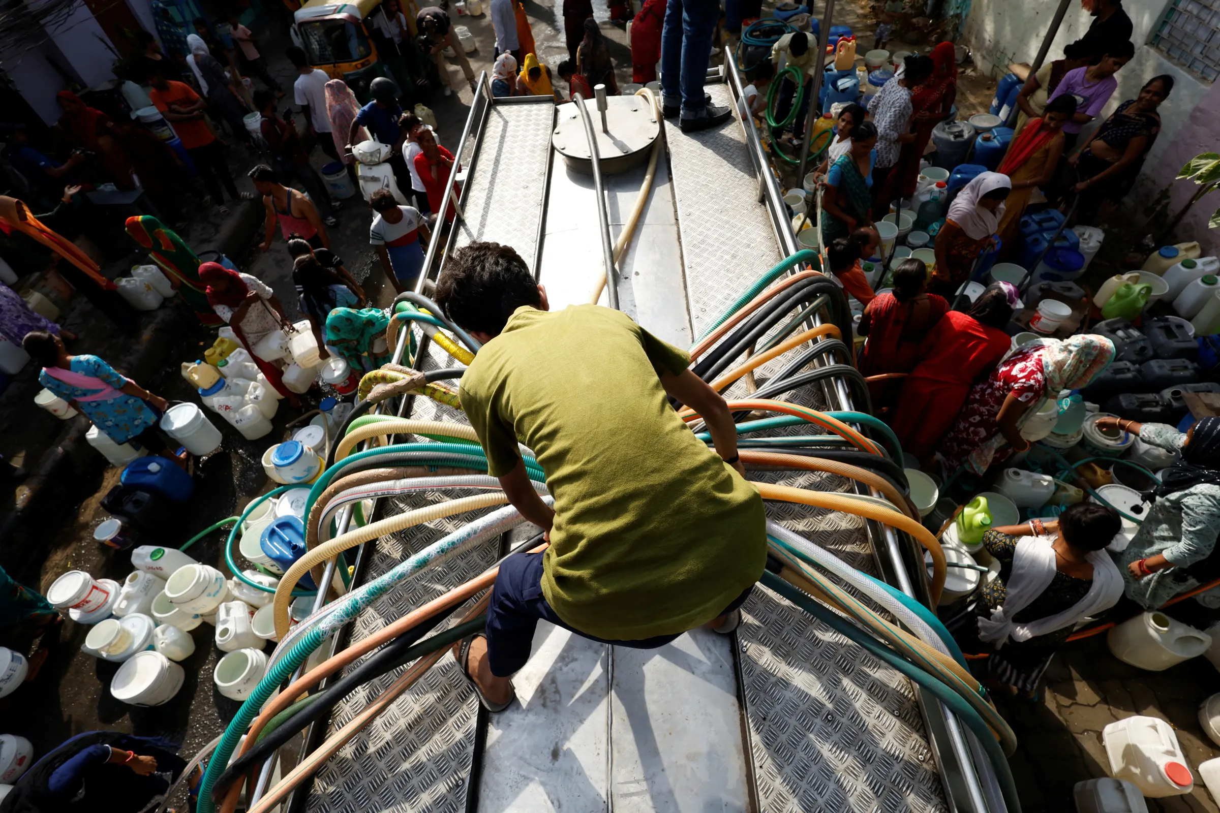 Residents use pipes to fill their containers with drinking water from a water tanker during a hot day in New Delhi, India, June 13, 2024. REUTERS/Priyanshu Singh