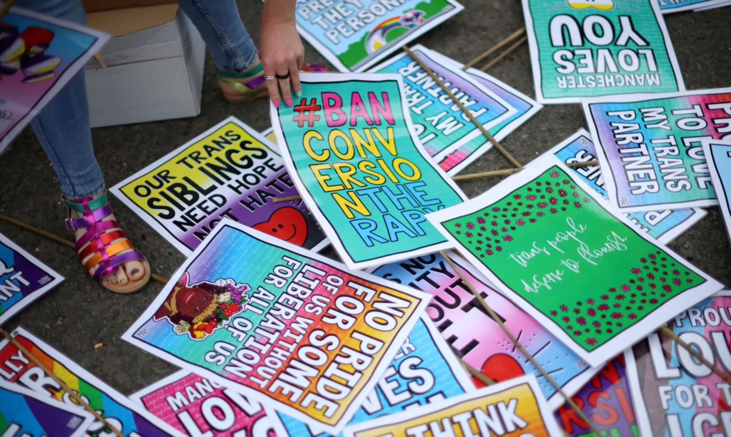 A person picks up a placard ahead of a 'Trans Joy March' as part of the Sparkle, a gender diversity festival in Manchester, Britain, July 8, 2023. REUTERS/Phil Noble
