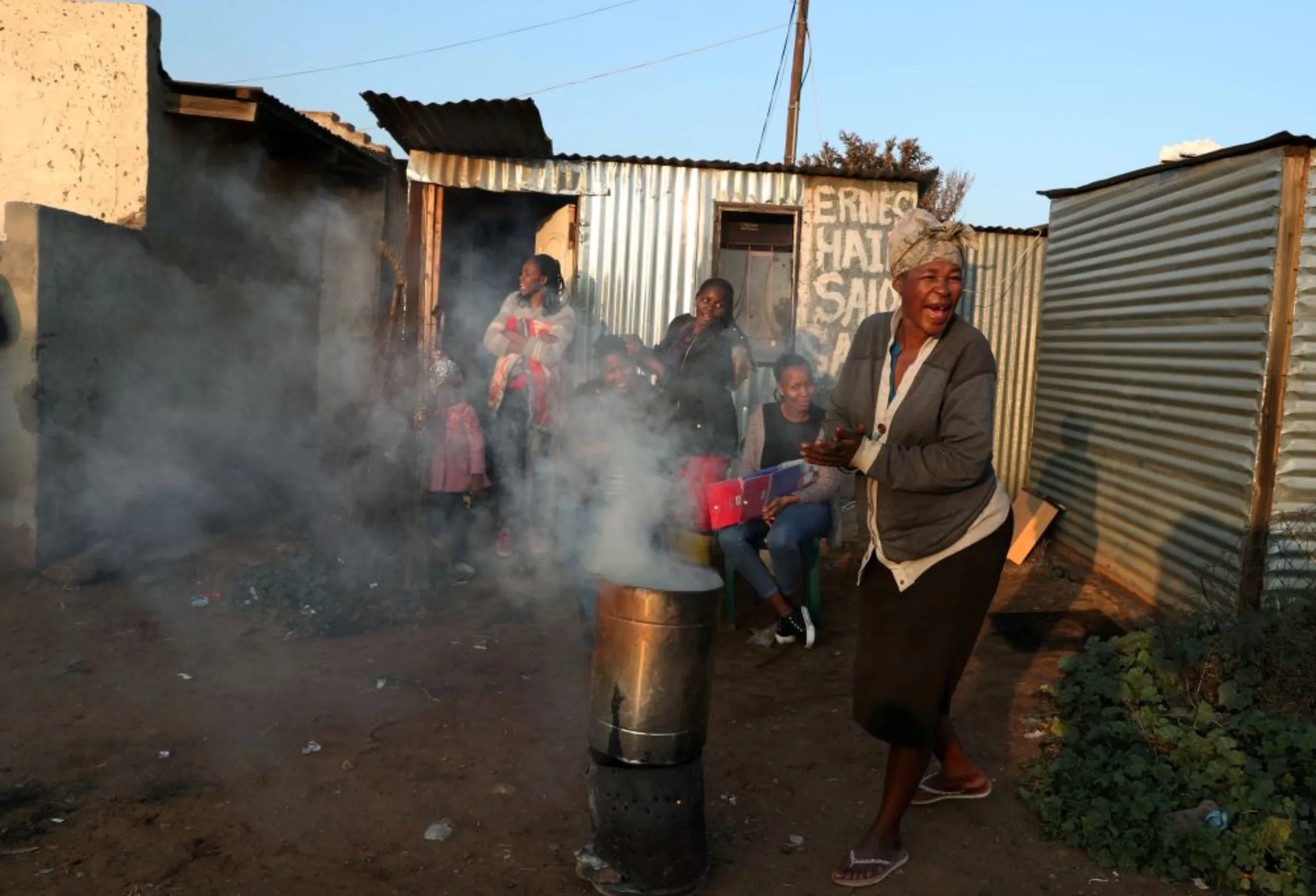 A woman reacts as she prepares a brazier in front of a makeshift hair saloon, during electricity outages in Soweto, South Africa, June 19,2020