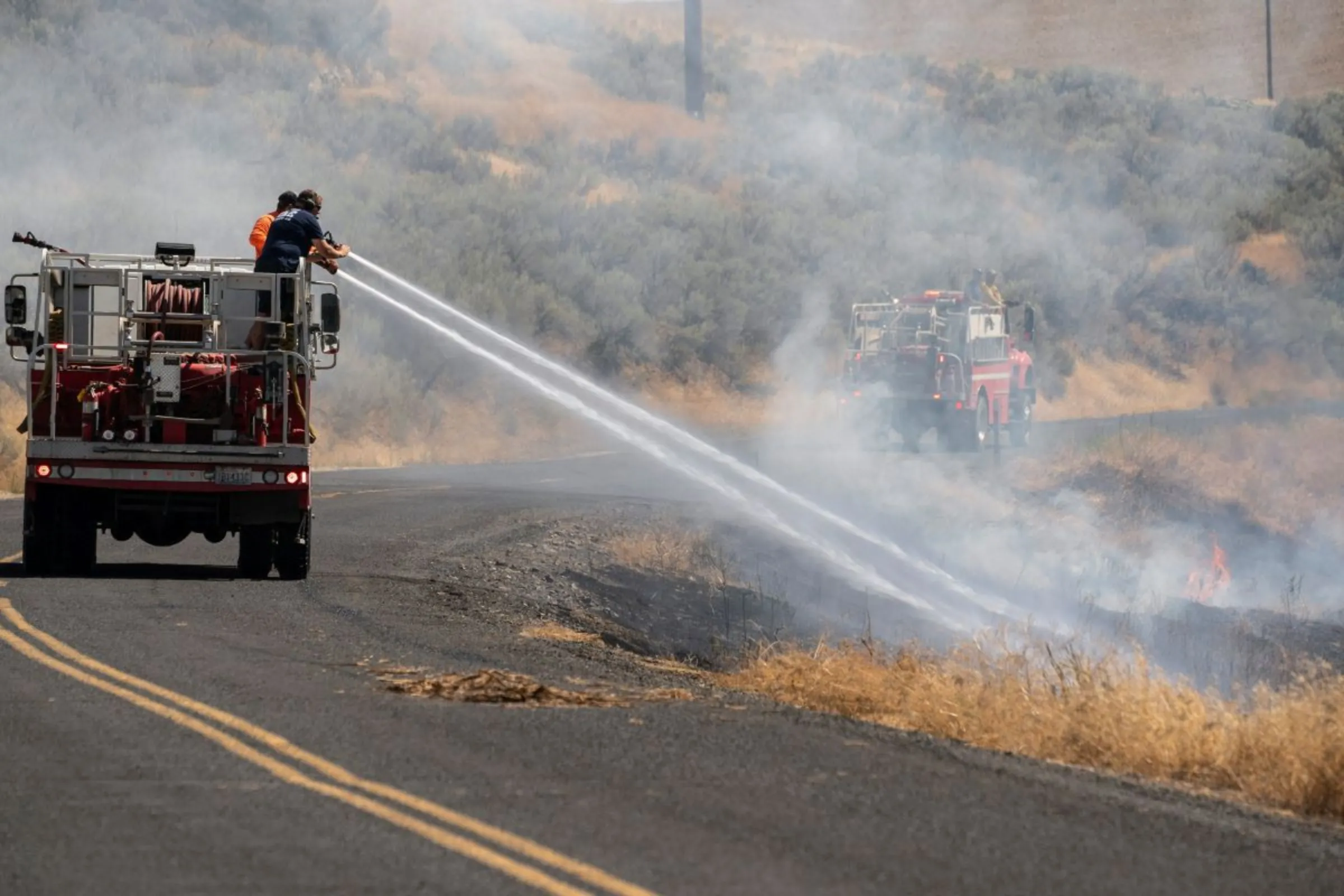 A firefighter truck extinguishes a flare up along a country road a day after a wildfire in the town of Lind, Washington, U.S., August 5, 2022. REUTERS/David Ryder