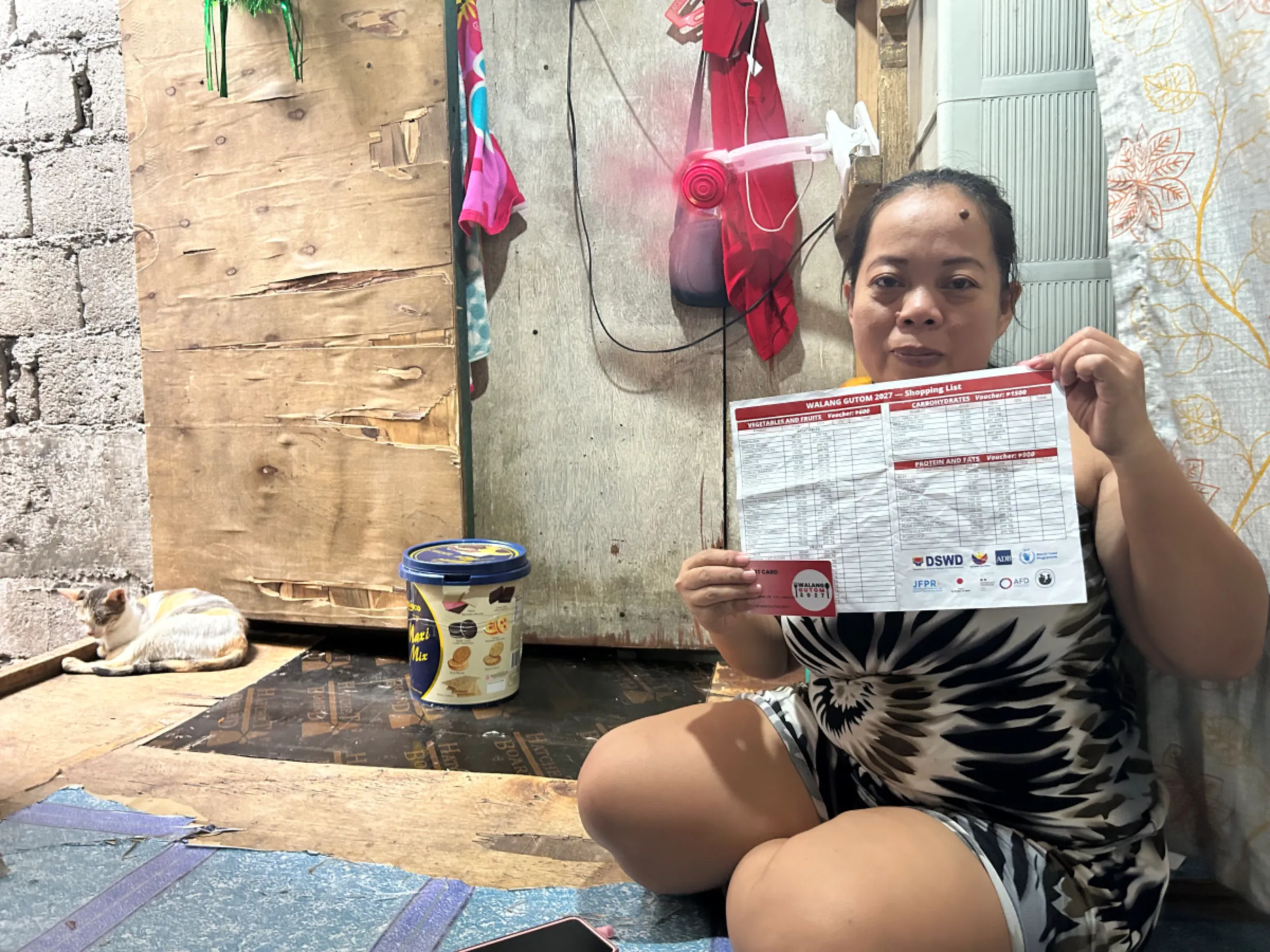 Mindalyn Villanueva of Tondo, a beneficiary of the Philippine government's Walang Gutom national food stamp programme shows her electronic benefit transfer card and grocery list. Manila, Philippines, December 7, 2023