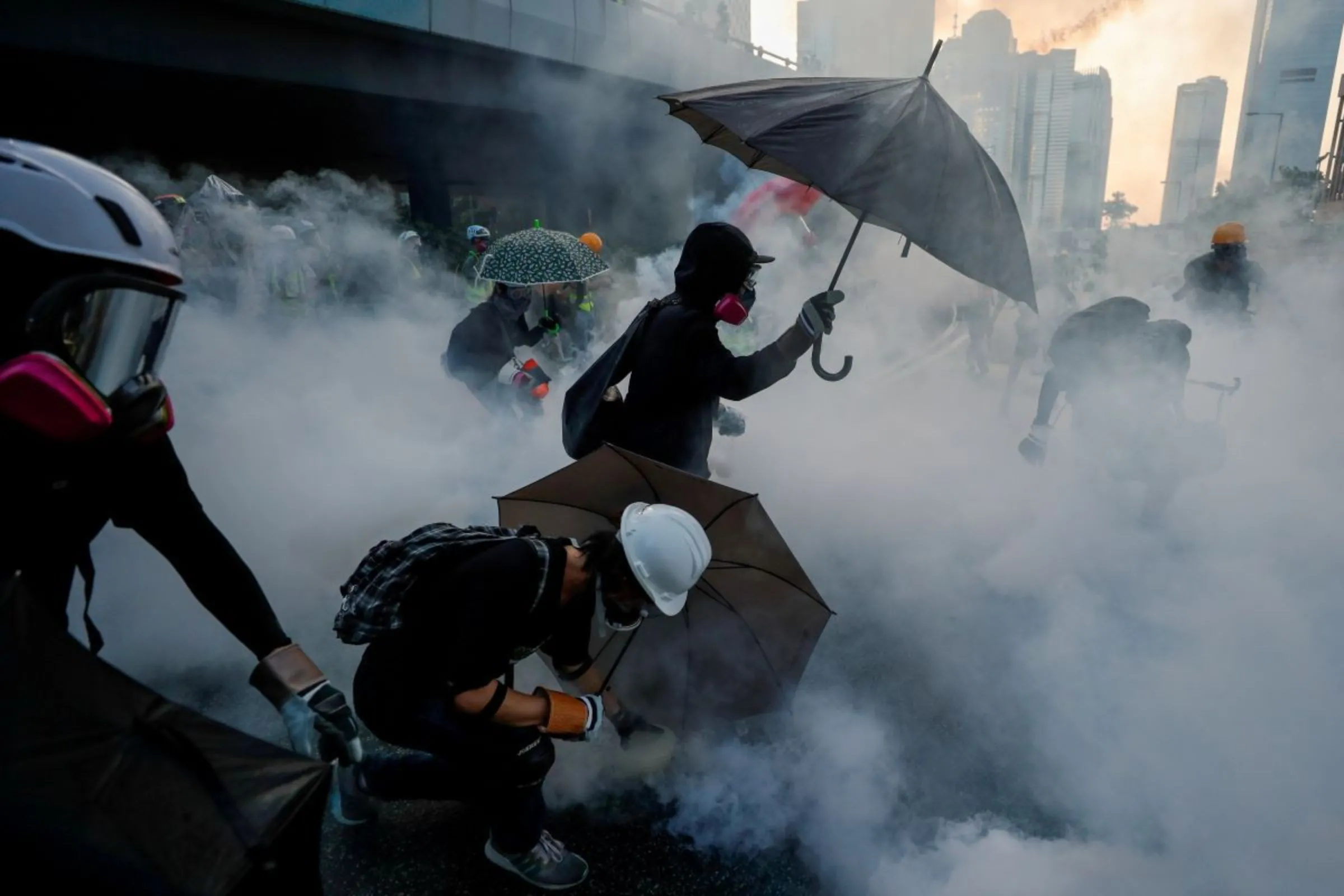 Anti-government protesters protect themselves with umbrellas among tear gas during a demonstration near Central Government Complex in Hong Kong, China, September 15, 2019