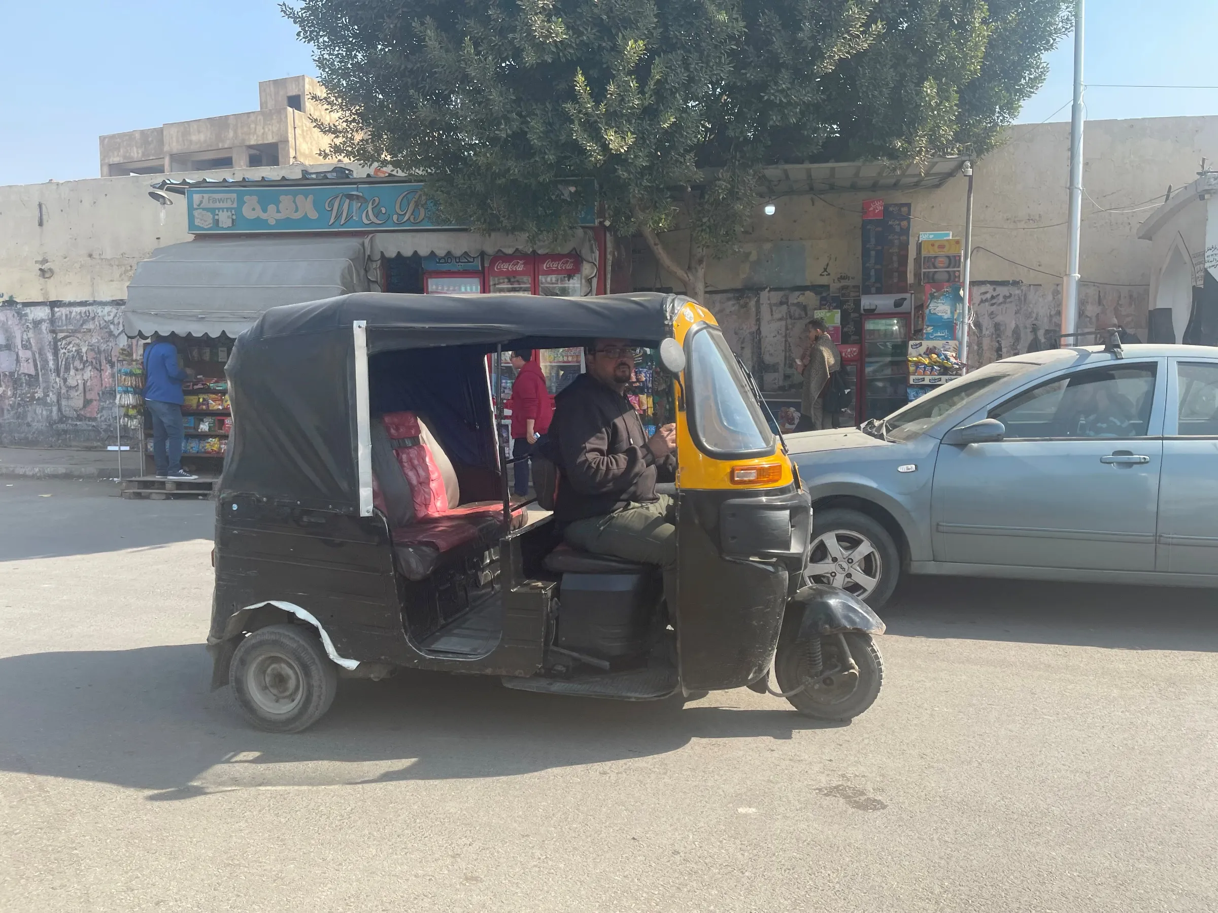 A three-wheeled tuk-tuk drives through the streets of eastern Cairo