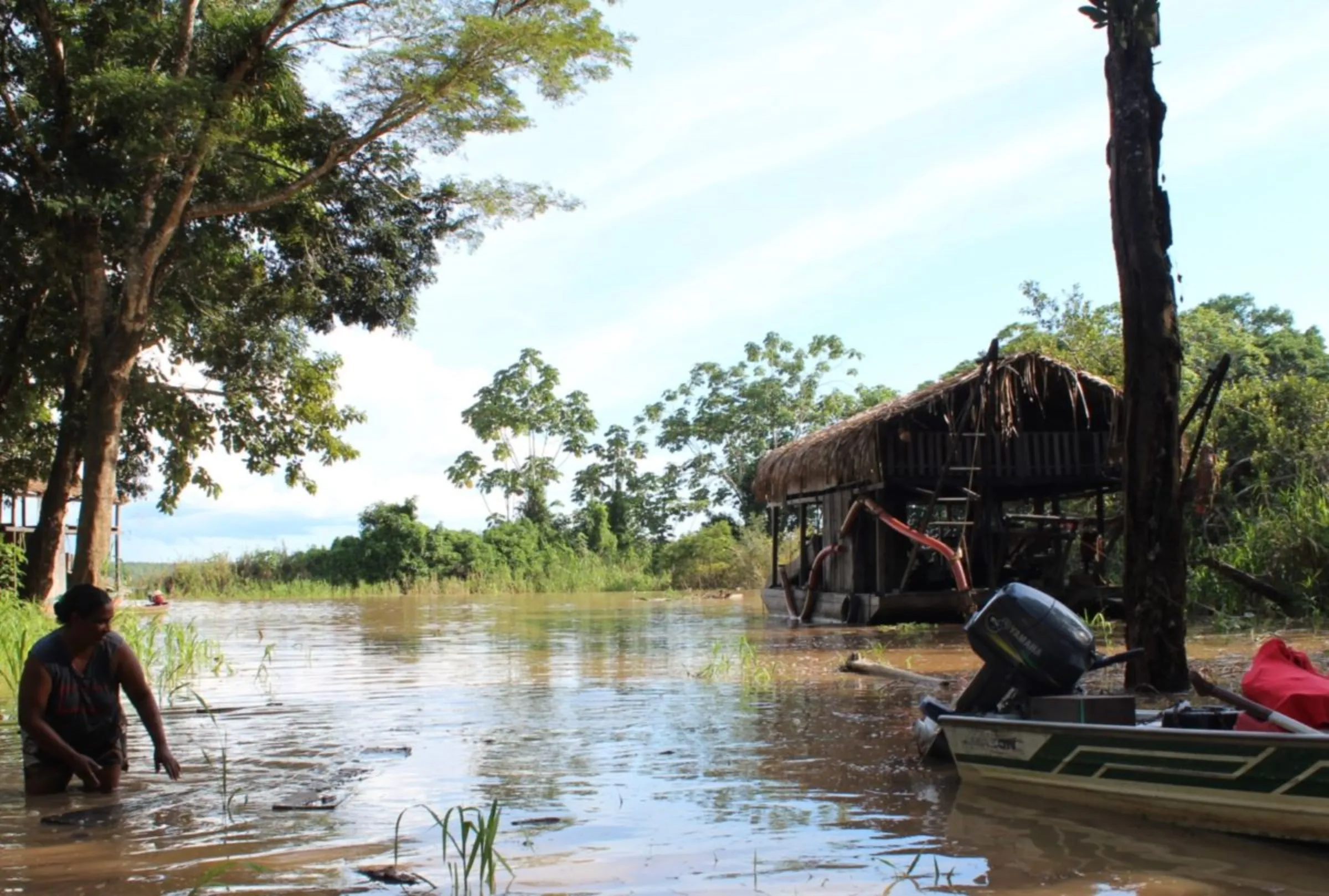 A woman walks by a beach near a mining barge in Humaitá, Brazil, Feb. 28, 2024. Thomson Reuters Foundation/André Cabette Fábio