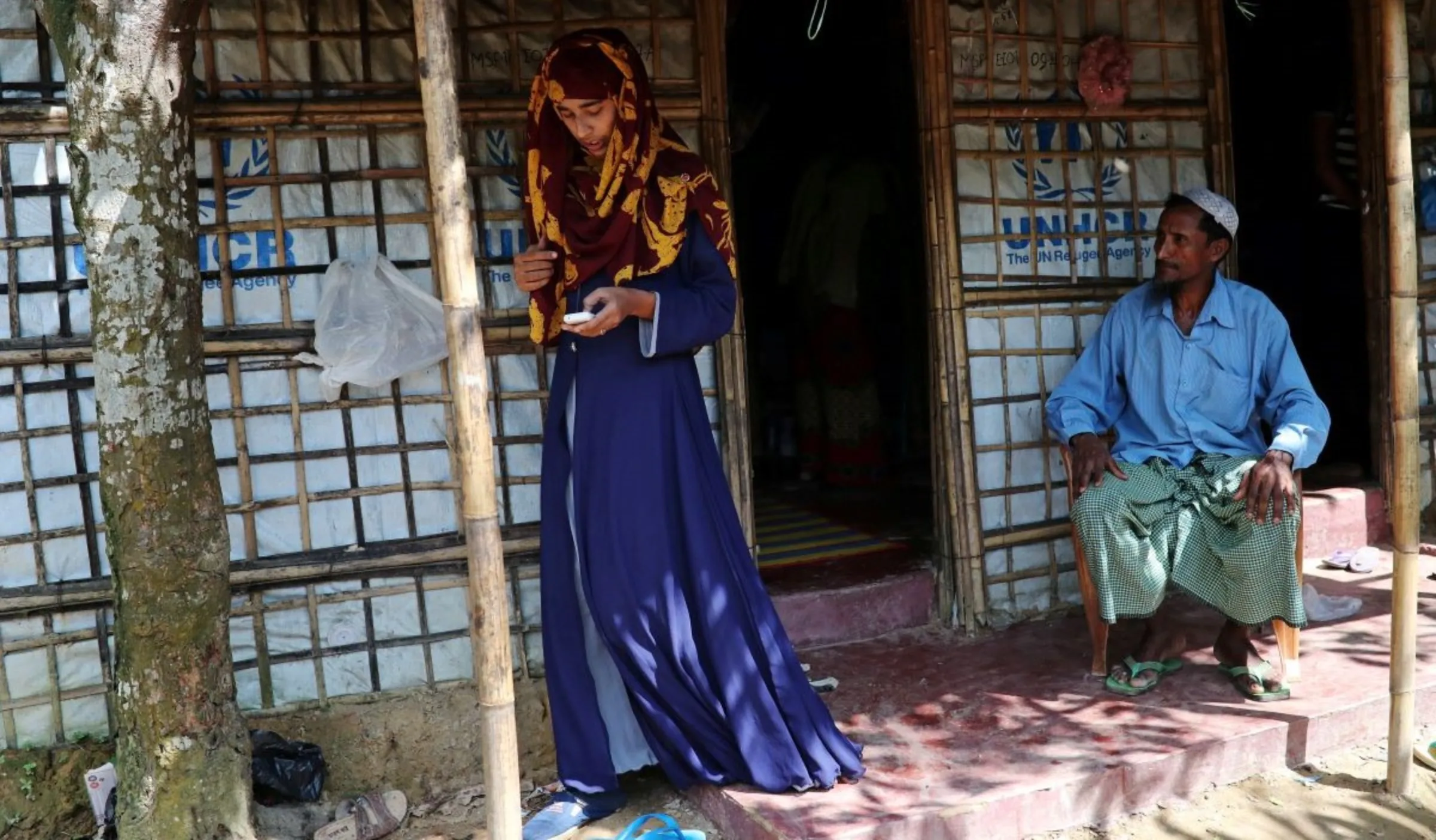 A girl uses her mobile phone as her father watches in Cox's Bazar, Bangladesh, August 24, 2018. REUTERS/Mohammad Ponir Hossain