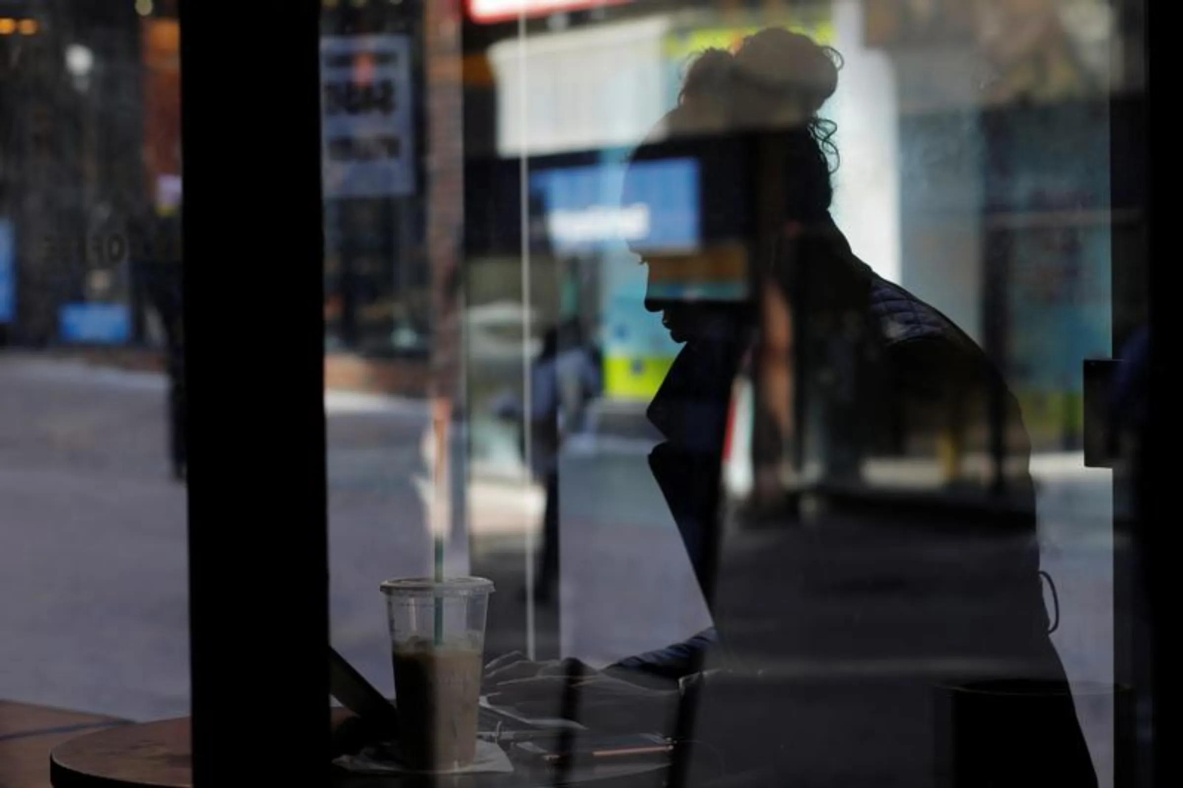 A woman is silhouetted in the window of a Starbucks while she uses her laptop computer in Boston, Massachusetts, U.S., February 21, 2017. REUTERS/Brian Snyder
