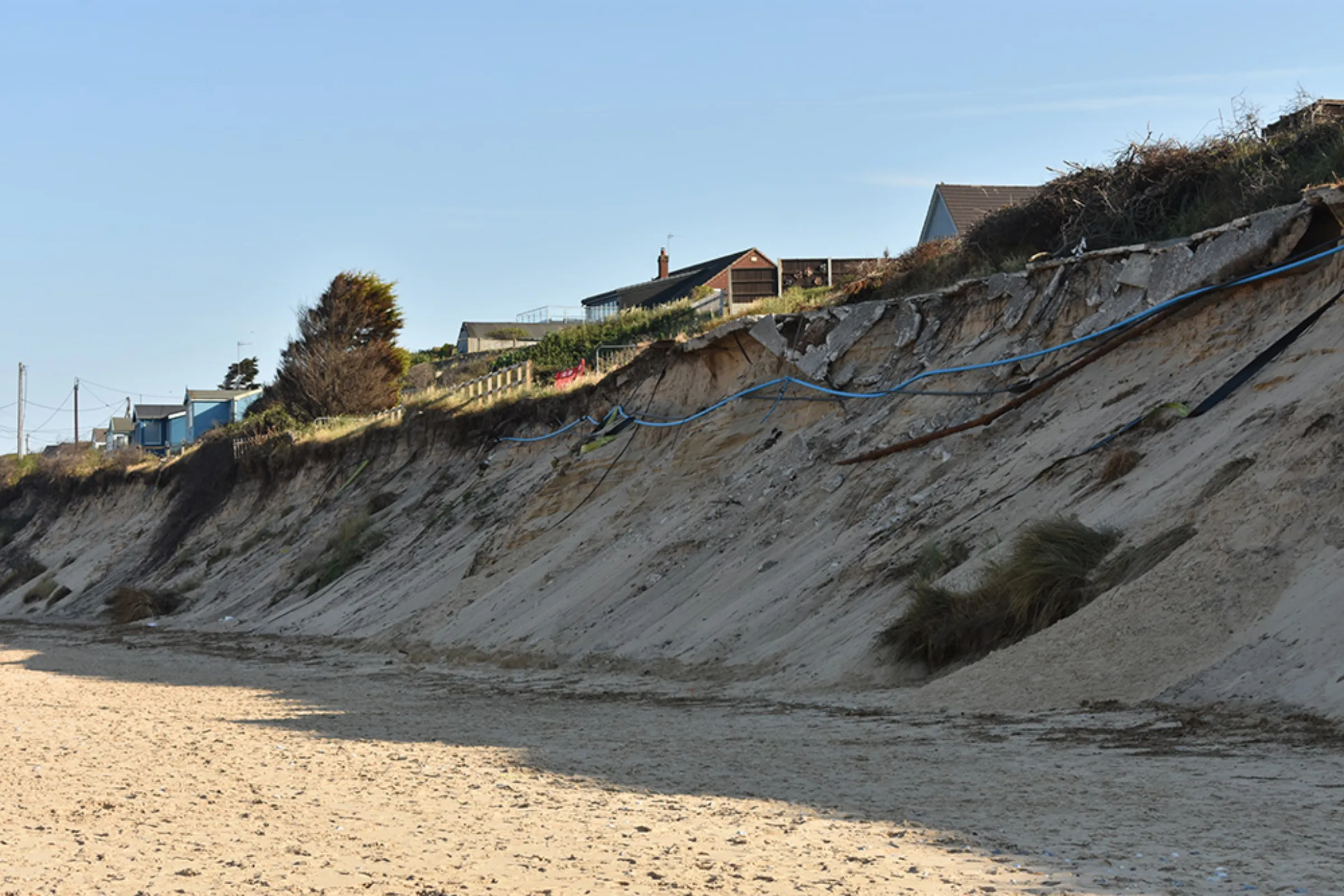 Fragments of the road damaged in a March storm leading to Kevin Jordan’s home dangle off a cliff edge in Hemsby, England, June 15, 2023. Thomson Reuters Foundation/Rachel Parsons