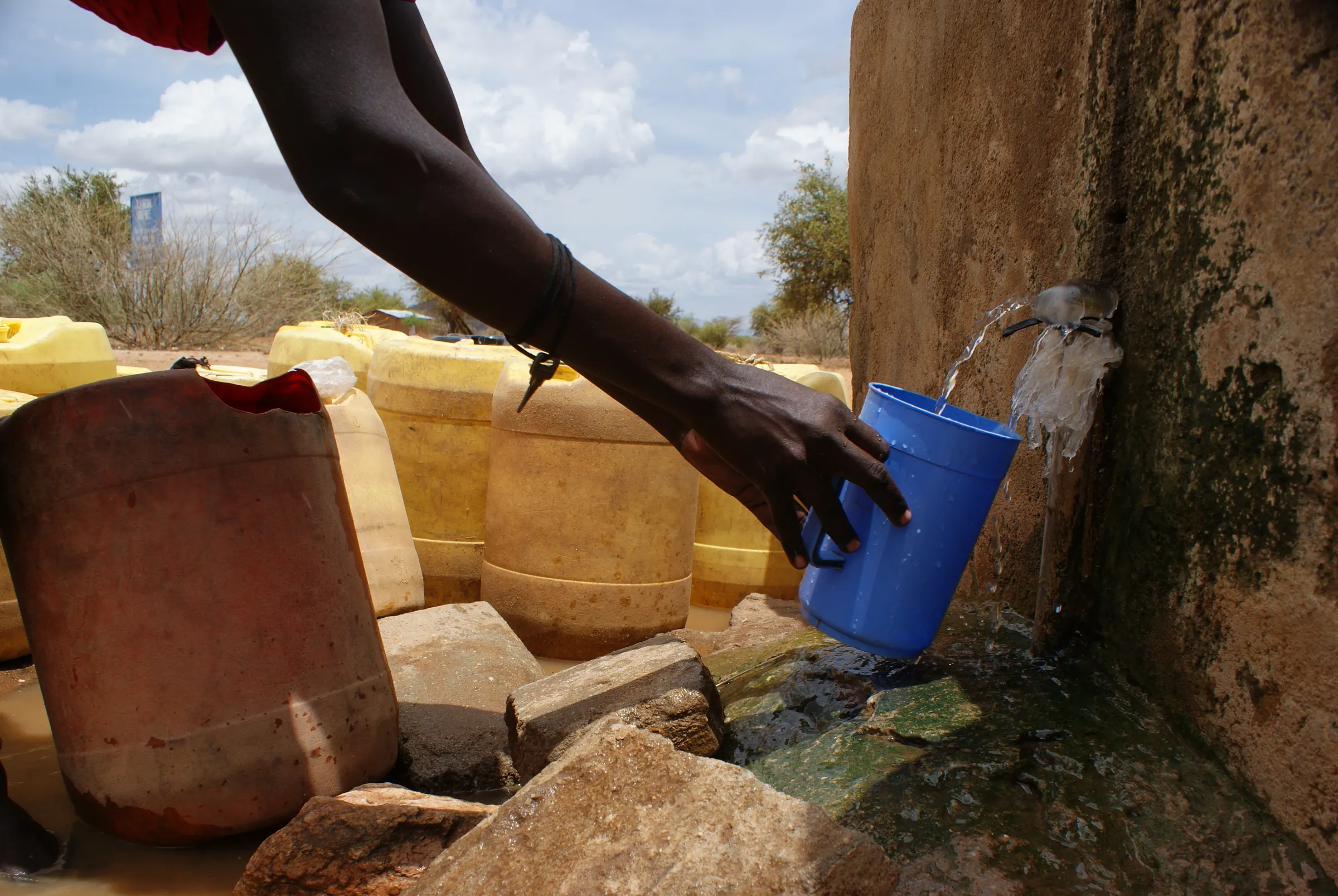 A resident fetches water at a tap built into a wall