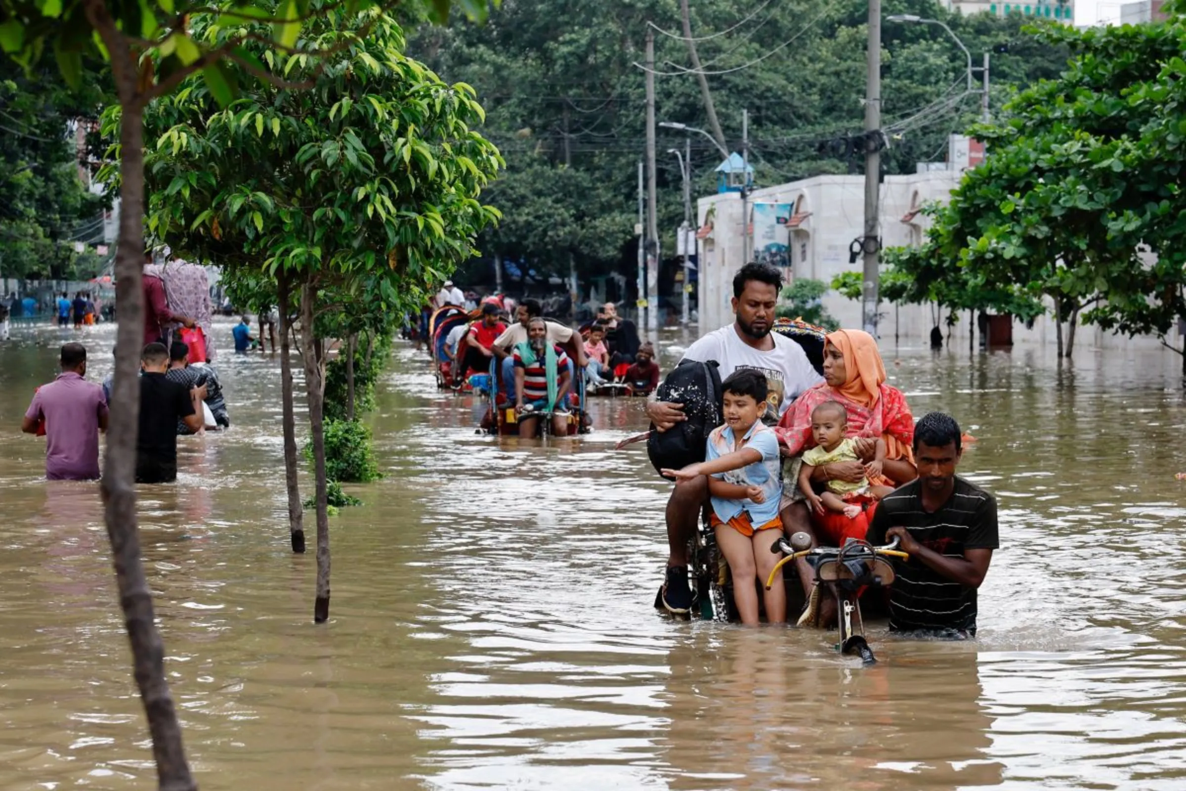 People move on rickshaws along a flooded street after a downpour in Dhaka, Bangladesh, July 12, 2024. REUTERS/Mohammad Ponir Hossain