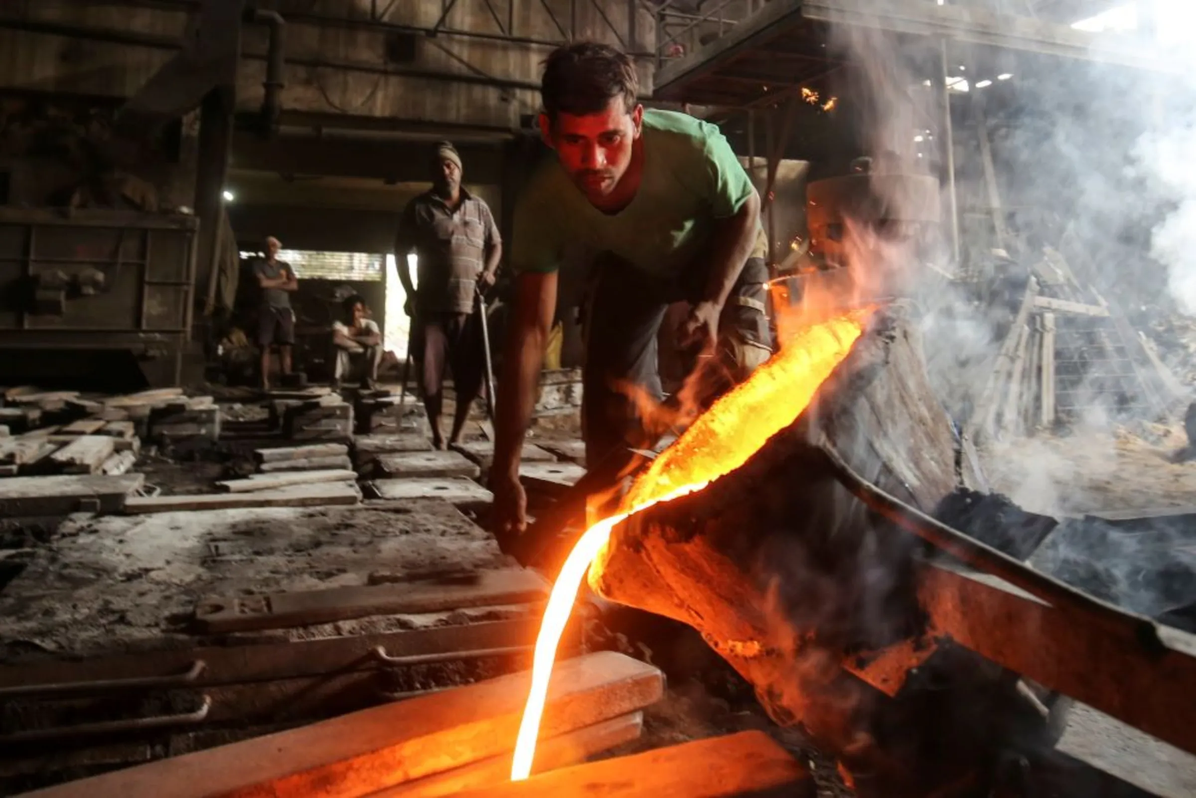 A worker pours molten iron from a ladle to make automobile spare parts inside an iron casting factory in Ahmedabad, India, January 31, 2019