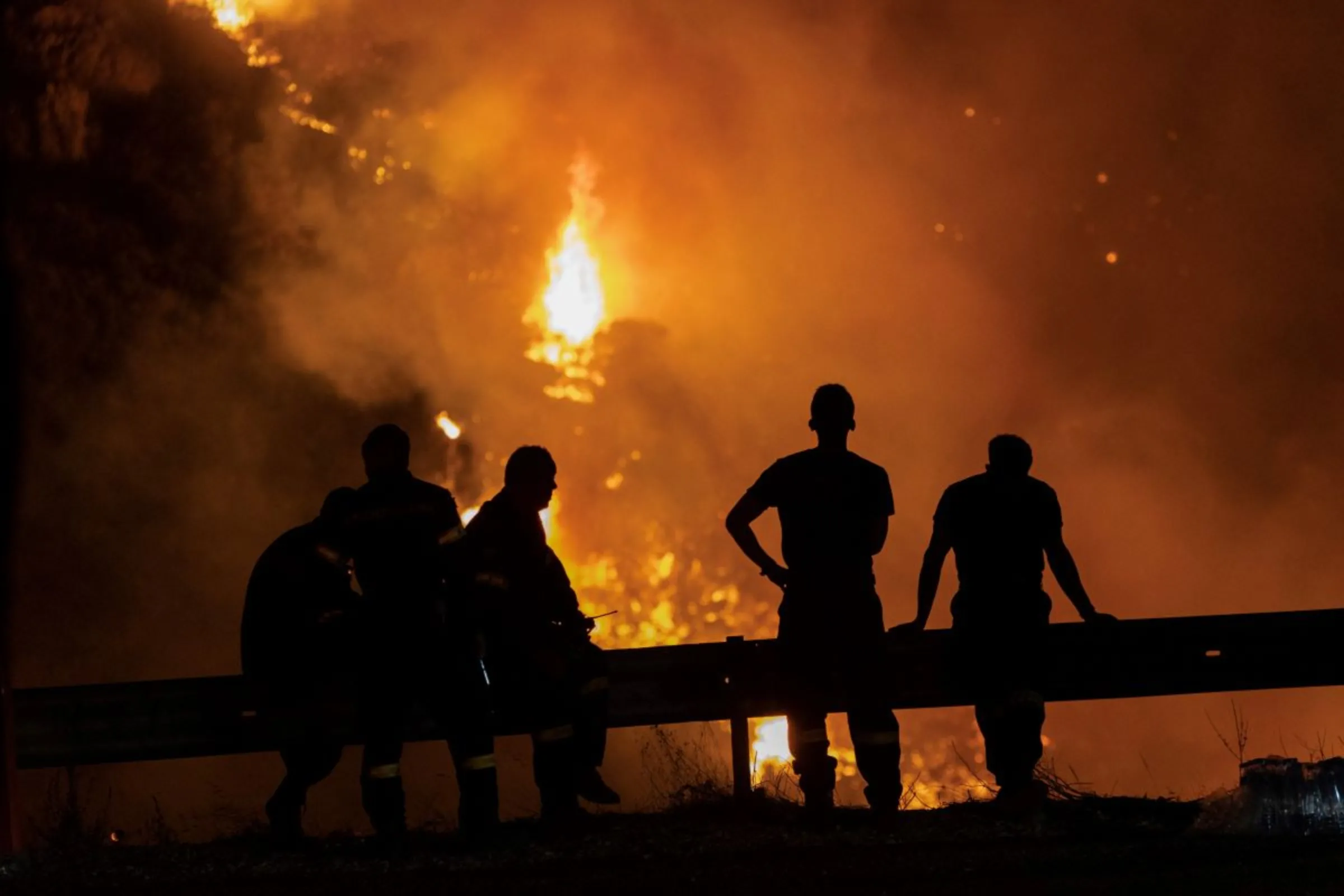 Firefighters look at a wildfire burning on Mount Parnitha, in Athens, Greece, August 24, 2023. REUTERS/Nicolas Economou