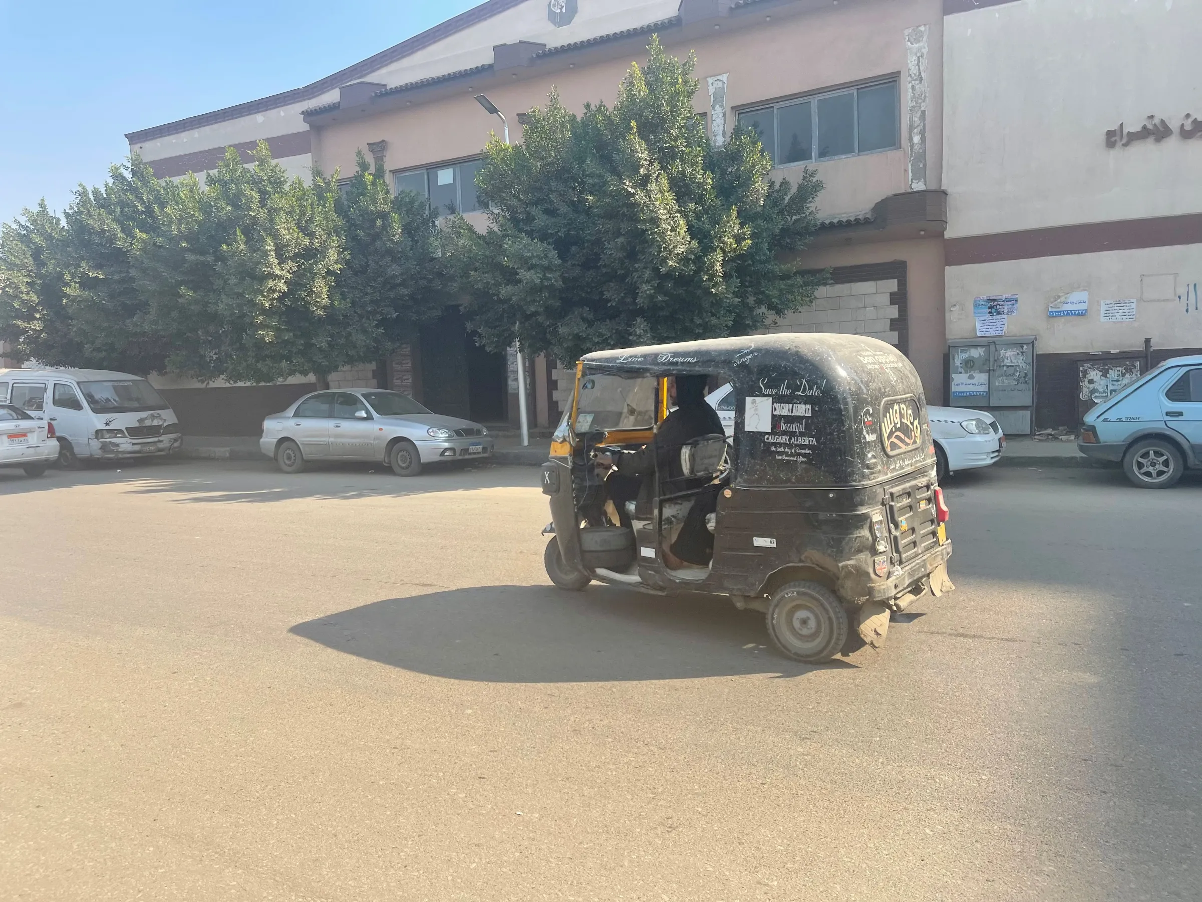 A three-wheeled tuk-tuk drives through the streets of eastern Cairo