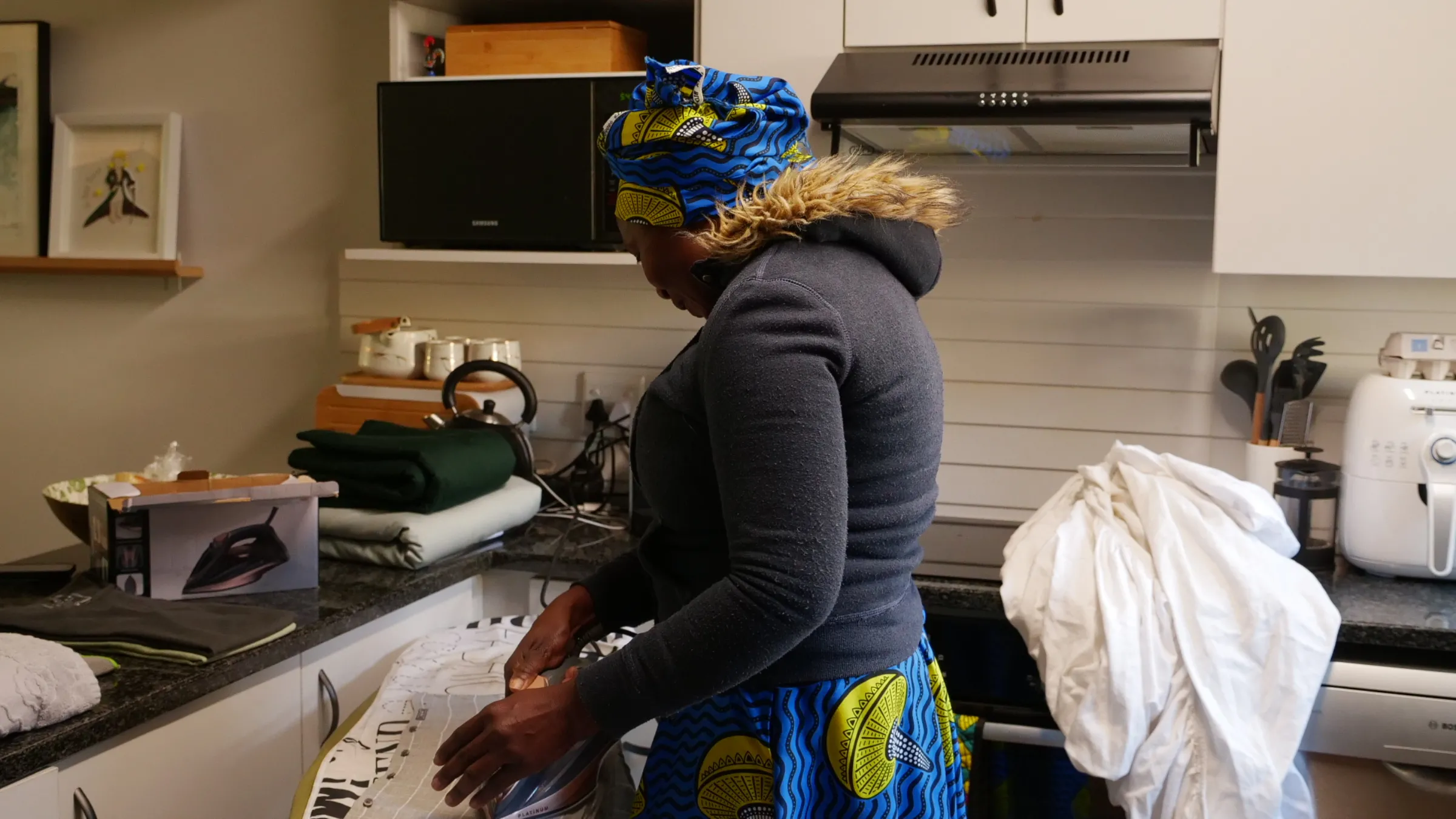 Nora, a Zimbabwean domestic worker living in Johannesburg, irons the clothes of her employer