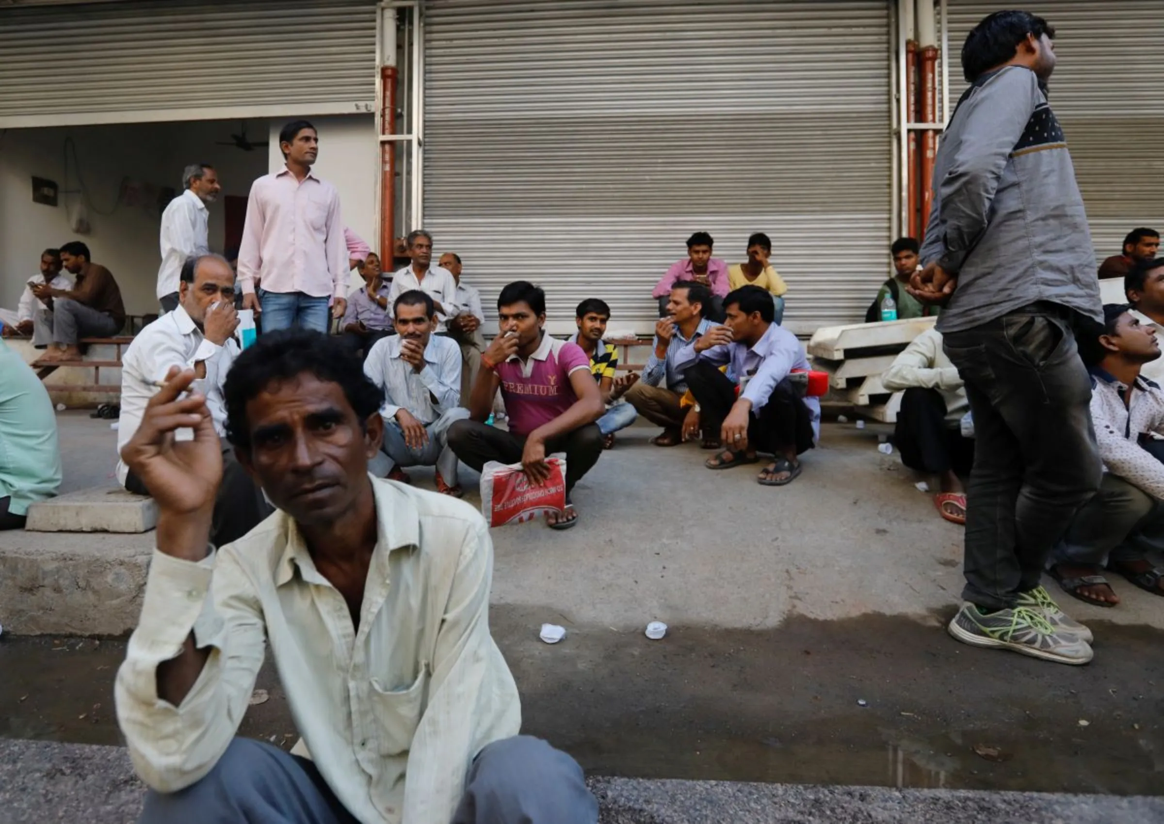 Tradespeople sit on the side of a road as they wait to get hired for work in Mumbai, India, November 6, 2017. REUTERS/Danish Siddiqui