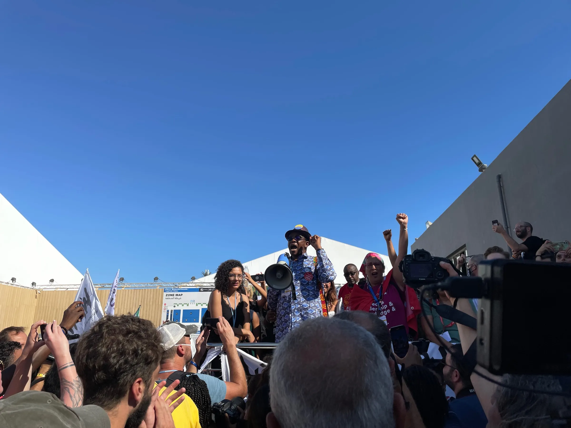 Nigerian environmental activist Nnimmo Bassey speaks at a climate justice march at the COP27 climate summit in Sharm el-Sheikh, Egypt, with Sanaa Seif, the sister of jailed hunger striker Alaa Abd el-Fattah, standing by his side (left), Nov. 12, 2022. Thomson Reuters Foundation/Megan Rowling