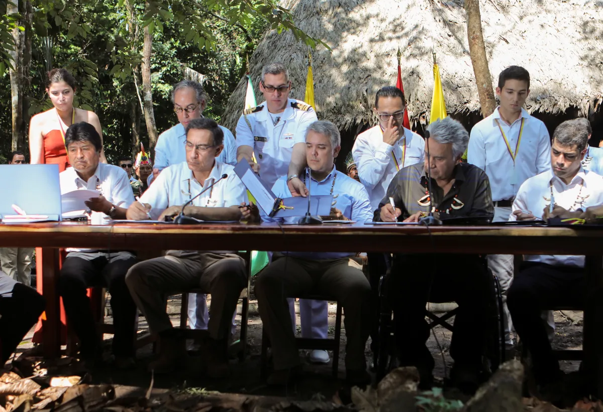 Officials sit at a table to sign a pact for the Amazon