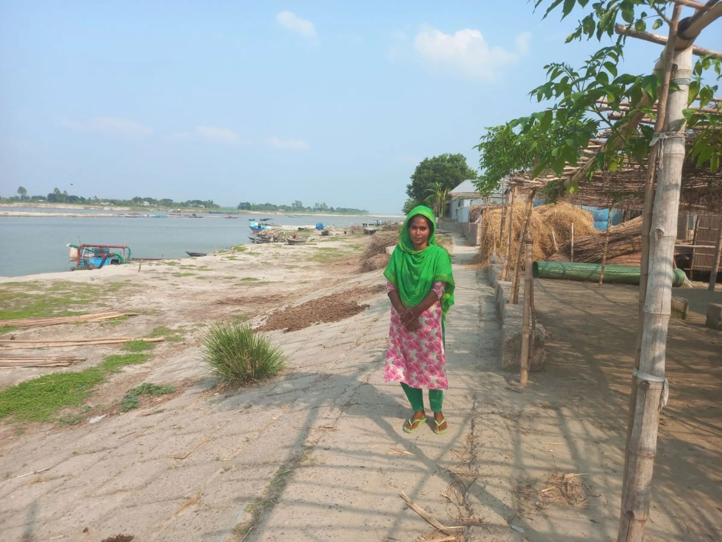 Sumi Akter, who raises goats and poultry to support her landless family, stands by the Padma River where floods and riverbank erosion have forced her to shift her house three times in the last three years, Faridpur, Bangladesh, May 21, 2023