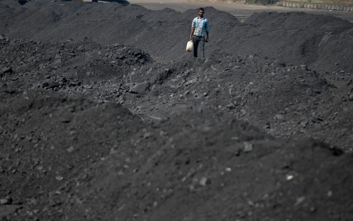 A worker carries a container filled with drinking water at a railway coal yard