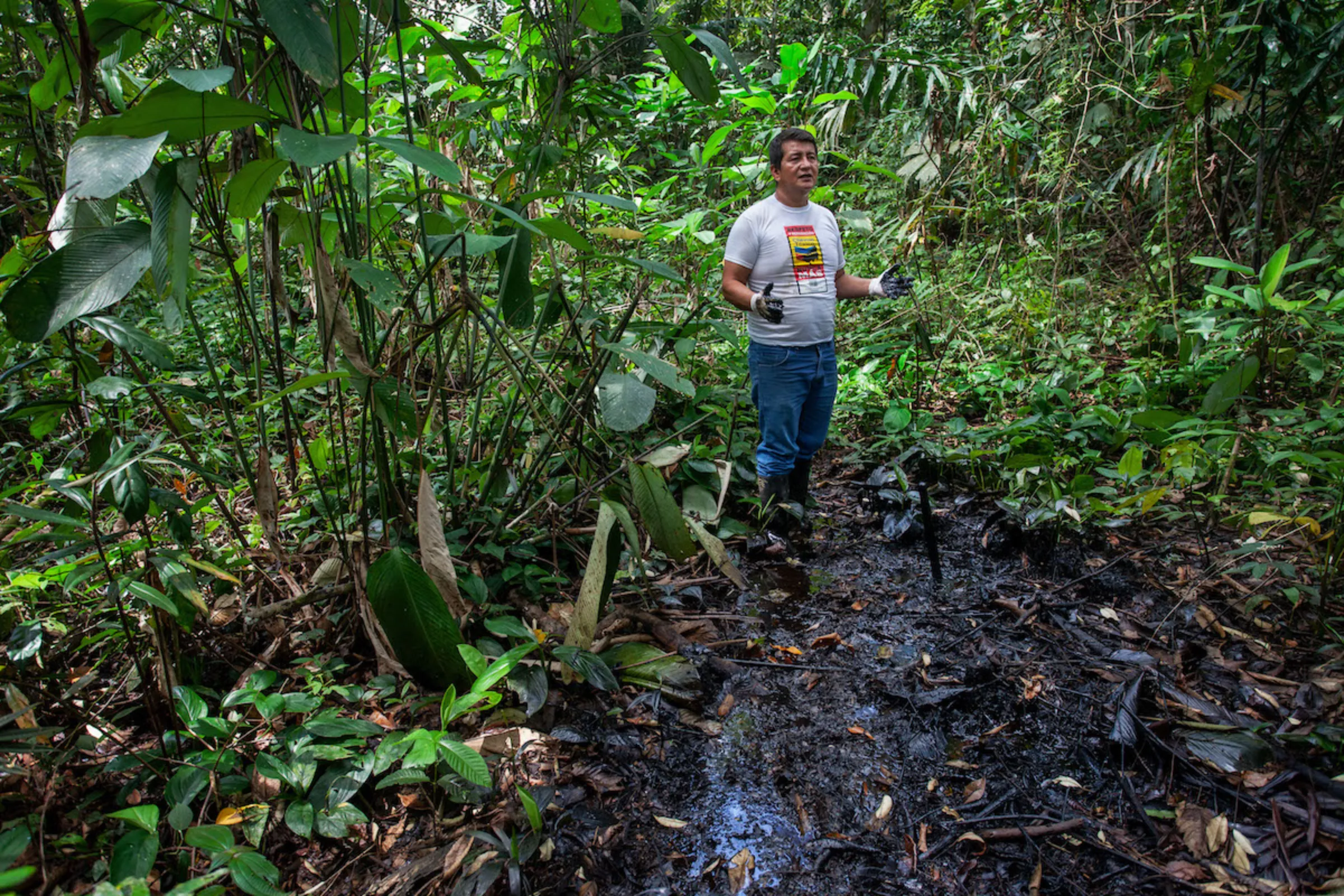 Campaigner Donald Moncayo stands in a waste pit of oil residue in the Amazon rainforest near Lago Agrio, Ecuador. April 23, 2022. Thomson Reuters Foundation/Fabio Cuttica