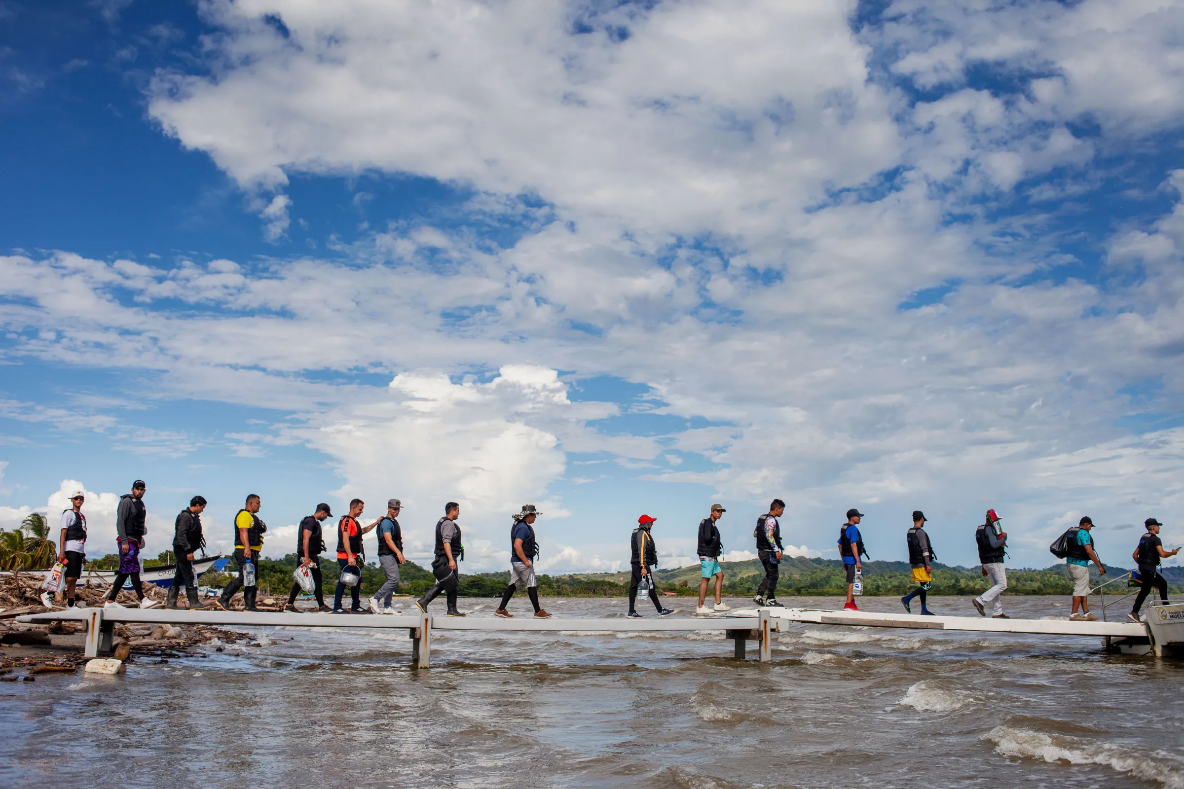 Wearing life jackets, migrants from Venezuela, Haiti, and parts of Africa and Asia board a tourist boat in Necoclí to cross the Gulf of Urabá to reach Capurganá from where the jungle trek begins. Migrants pay $40 for a two-hour ride. Necoclí, Colombia, July 26, 2022. Thomson Reuters Foundation/Fabio Cuttica