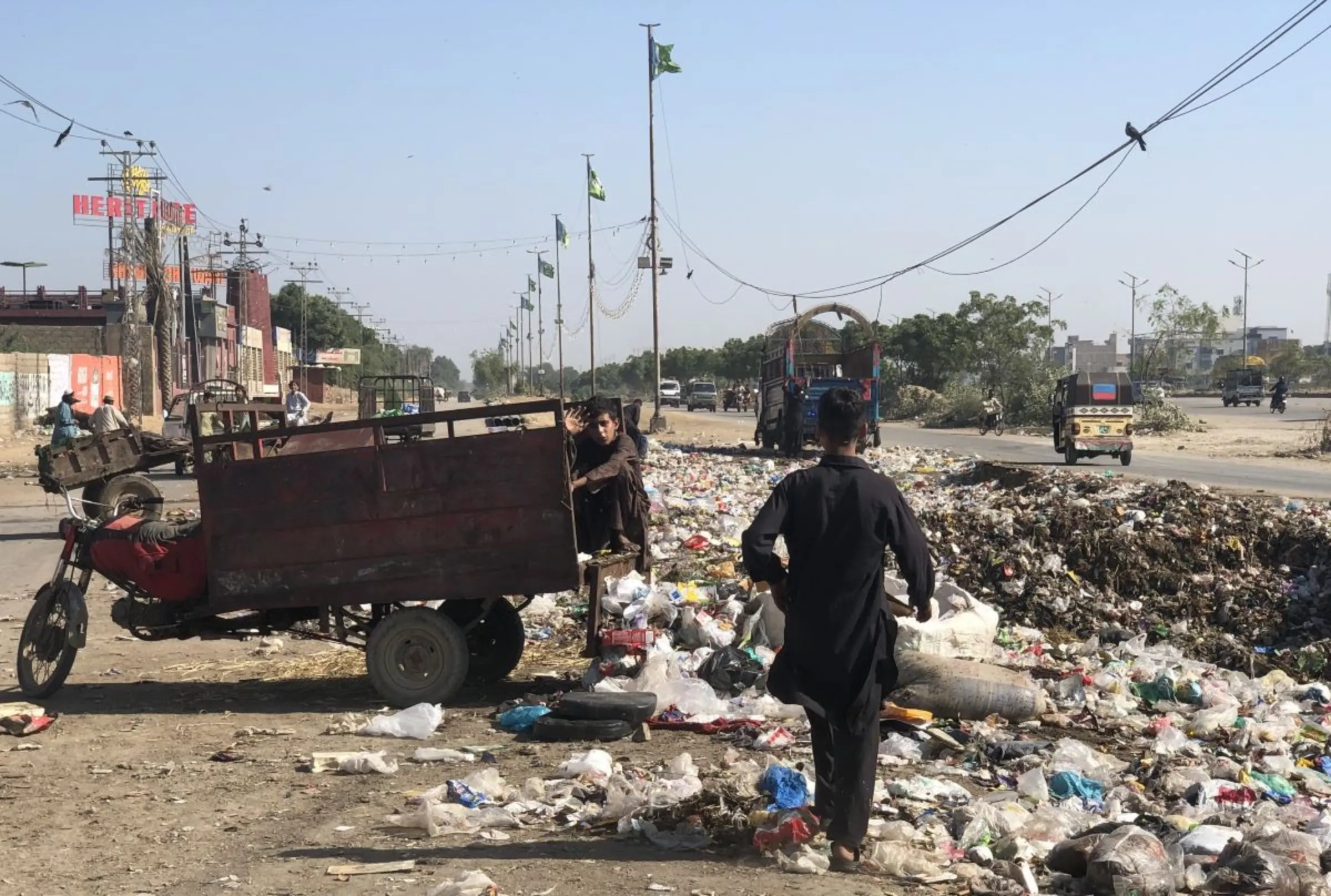 An Afghan child waste picker sits next to a roadside garbage heap near Al-Asif Square, Karachi, Pakistan, November 11, 2023