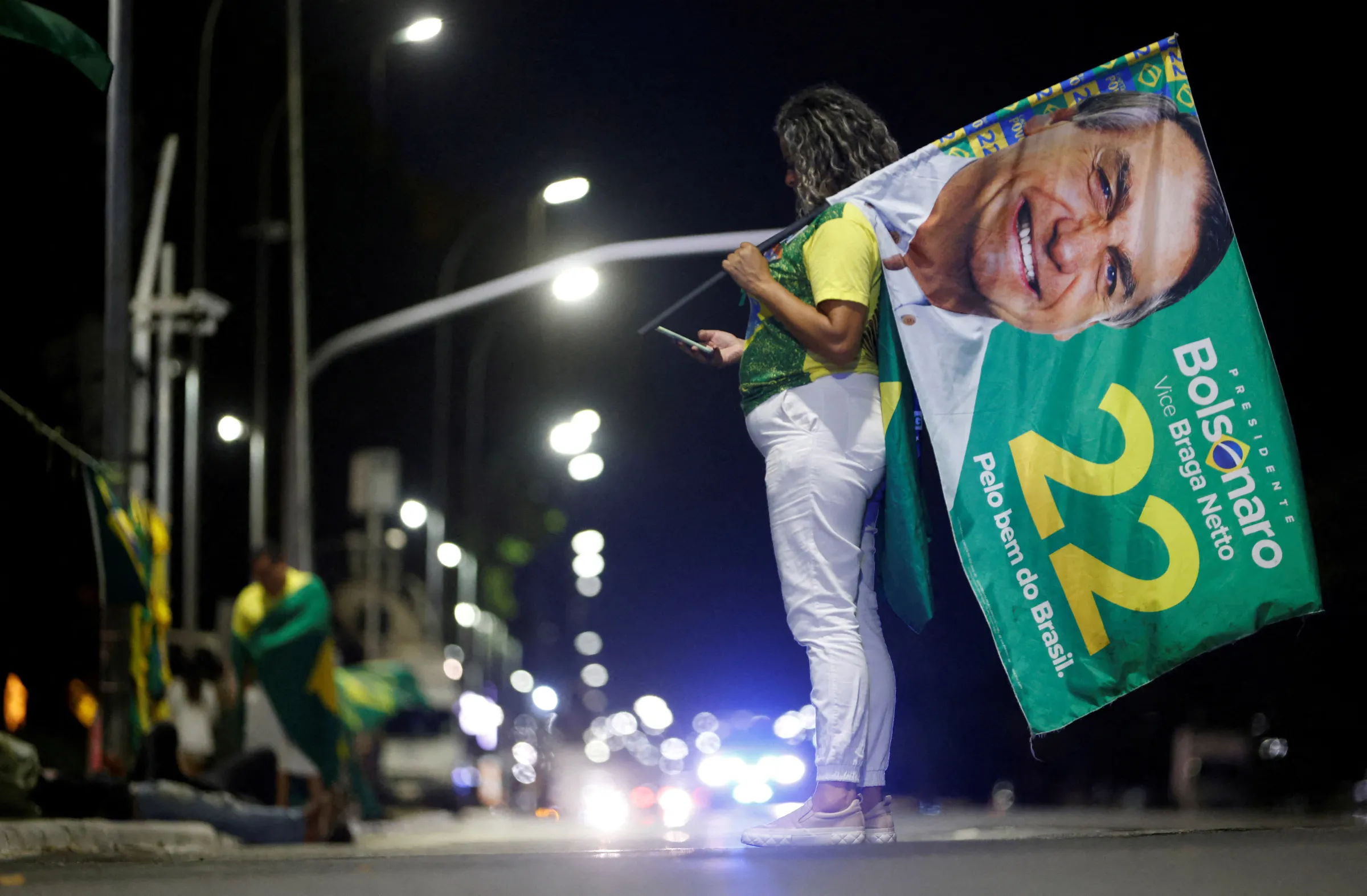 A supporter of Brazilian President Jair Bolsonaro looks at her mobile phone after polls were closed in Brazil's presidential election, in Brasilia, Brazil October 2, 2022. REUTERS/Adriano Machado