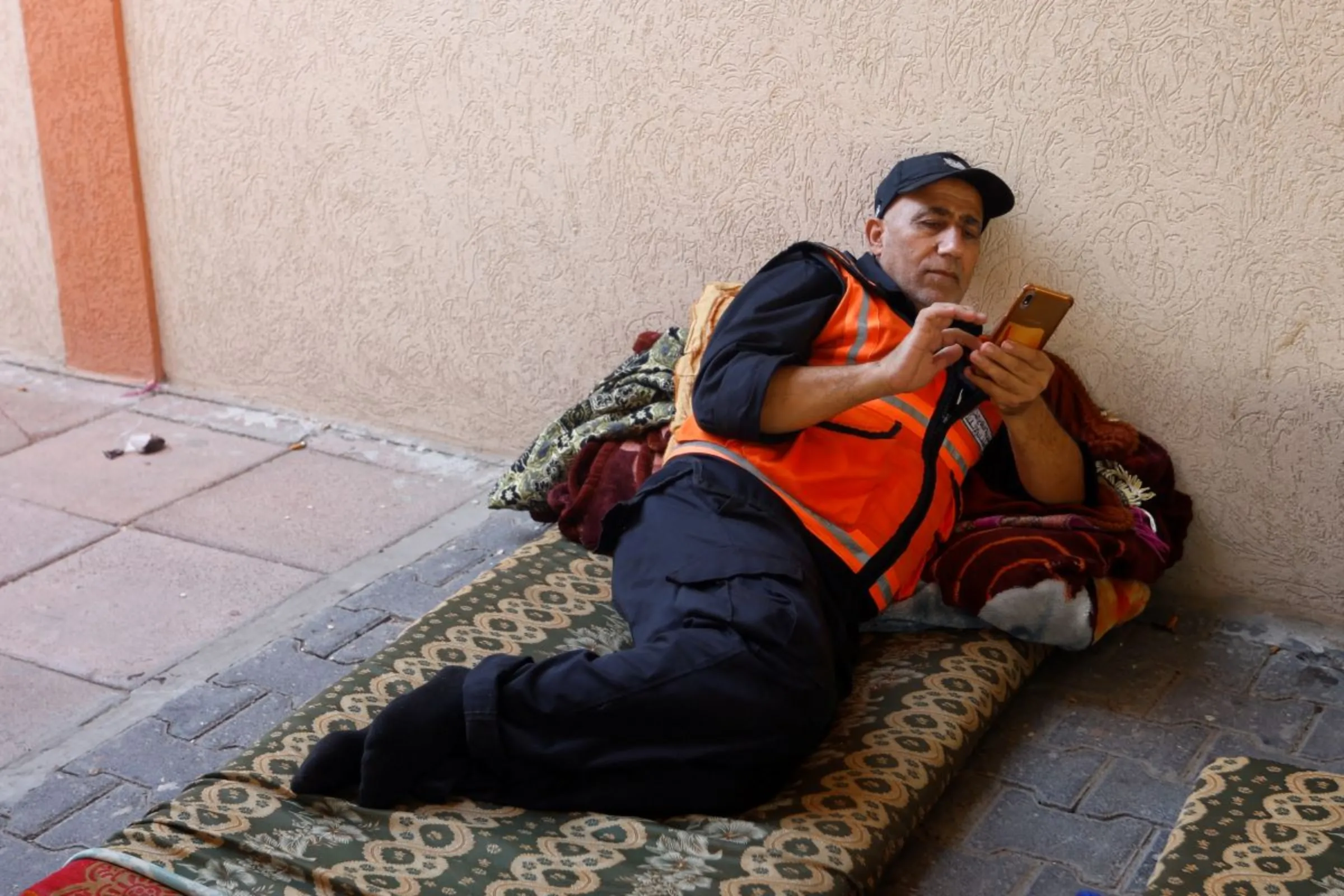 Palestinian emergency personnel checks his smart phone as he shelters in a school amid Israeli strikes in Khan Younis in the southern Gaza Strip October 12, 2023. REUTERS/Ibraheem Abu Mustafa