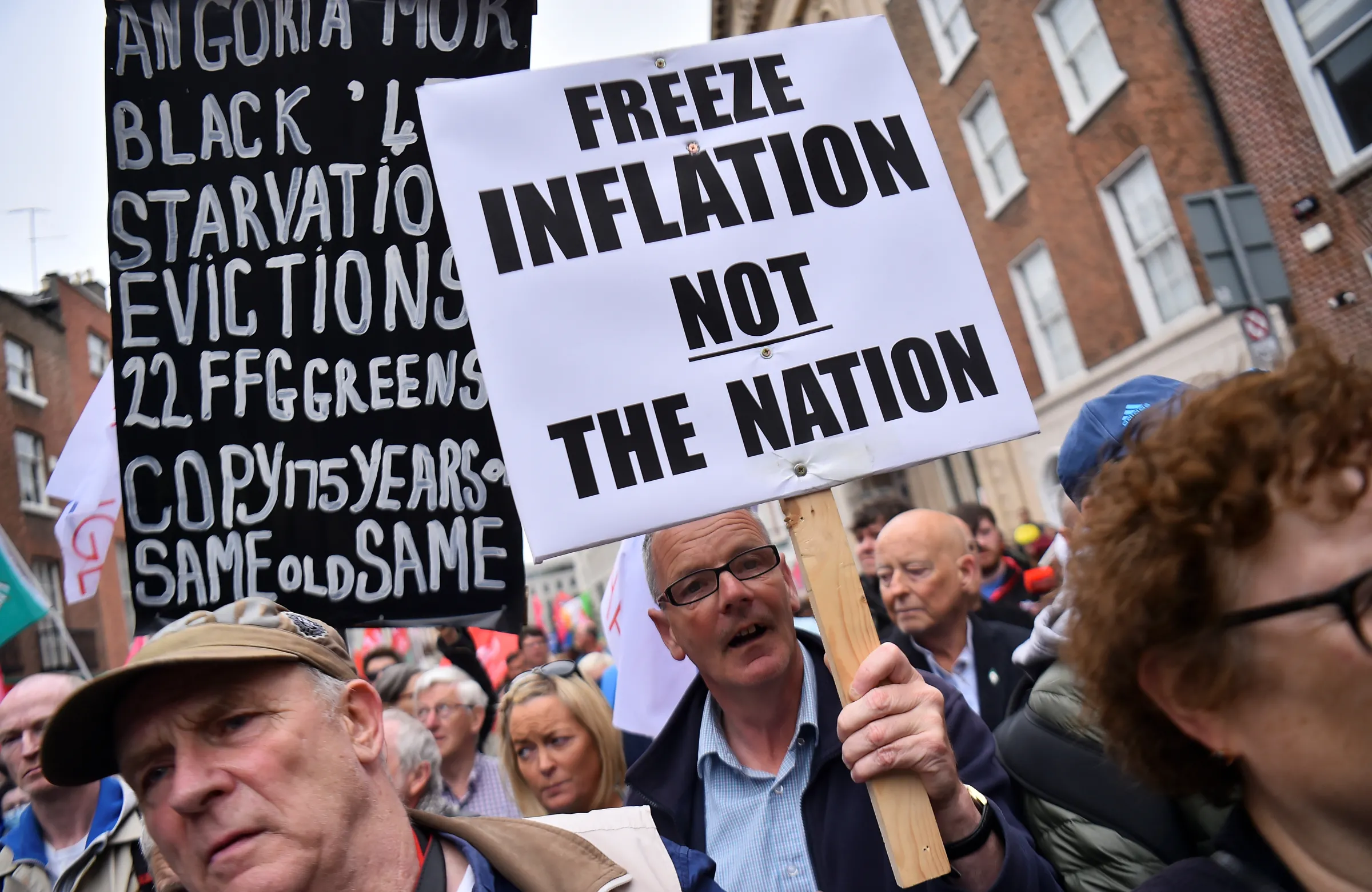 People hold signs and flags during a protest about the rising cost of living