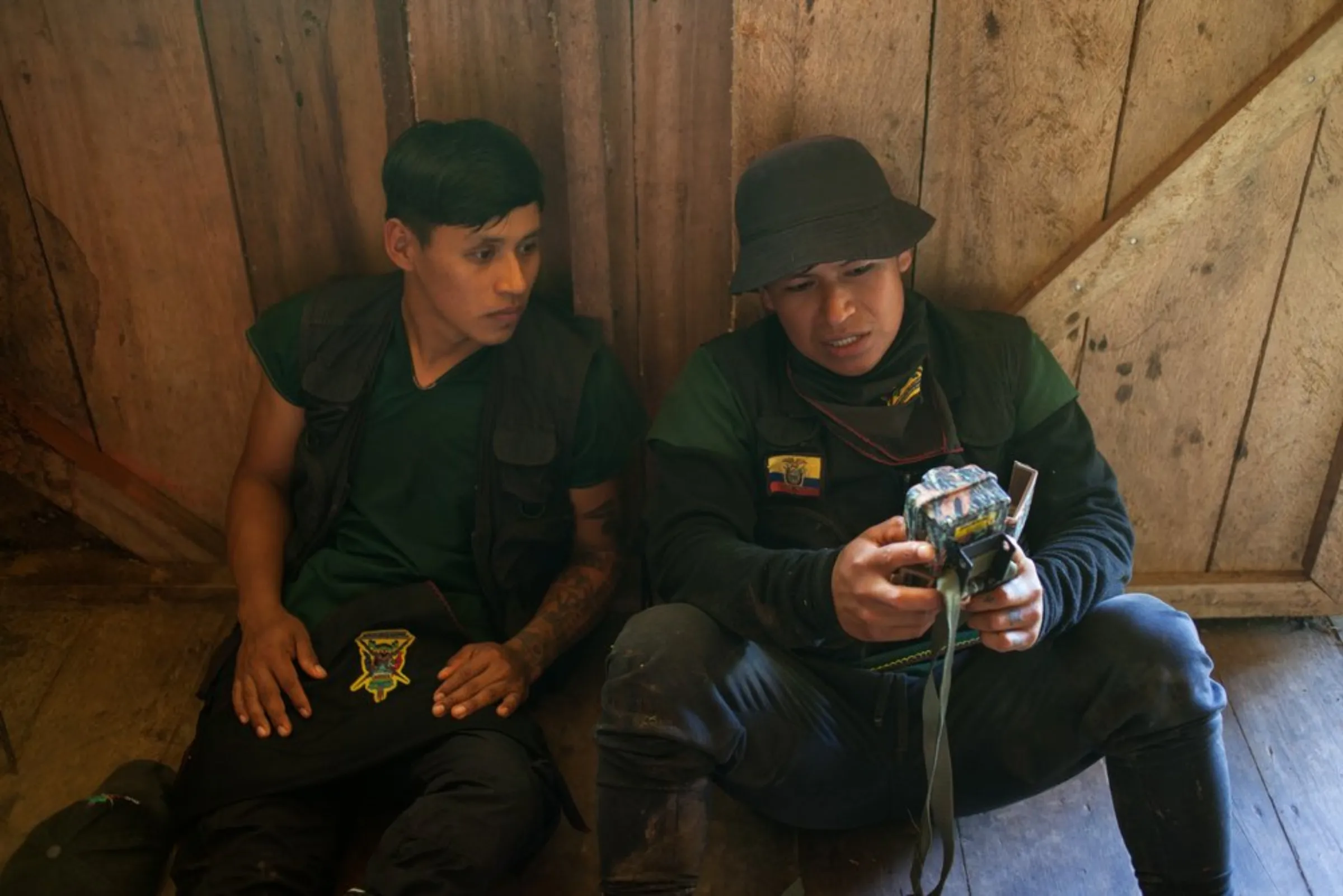 Marcelo Lucitante, a member of the Cofan indigenous guard, shows a fellow guard member footage from a camera trap used to record the passage of trespassing illegal gold miners, in Sinangoe, Ecuador, on April 21, 2022