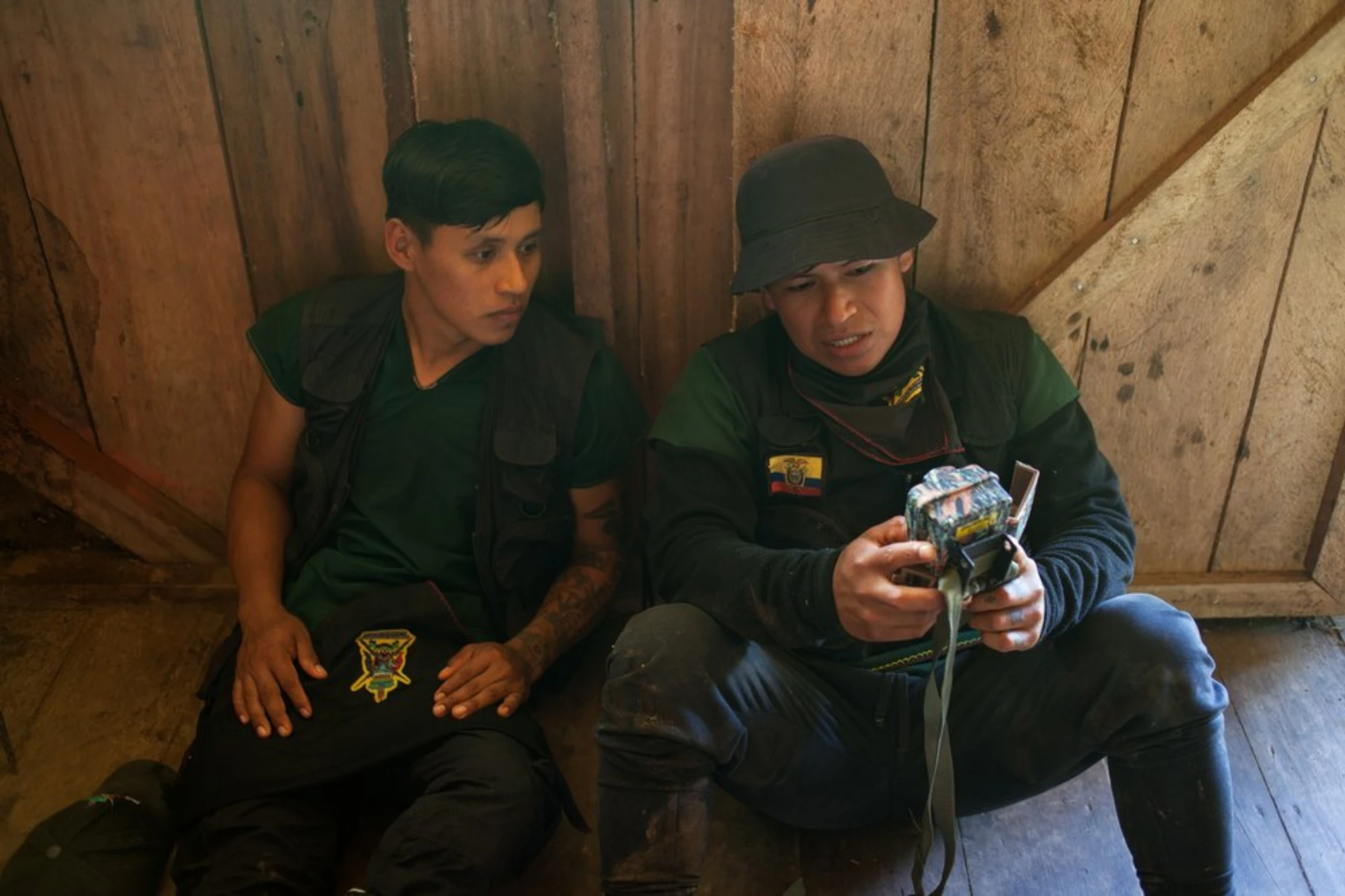 Marcelo Lucitante, a member of the Cofan indigenous guard, shows a fellow guard member footage from a camera trap used to record the passage of trespassing illegal gold miners, in Sinangoe, Ecuador, on April 21, 2022